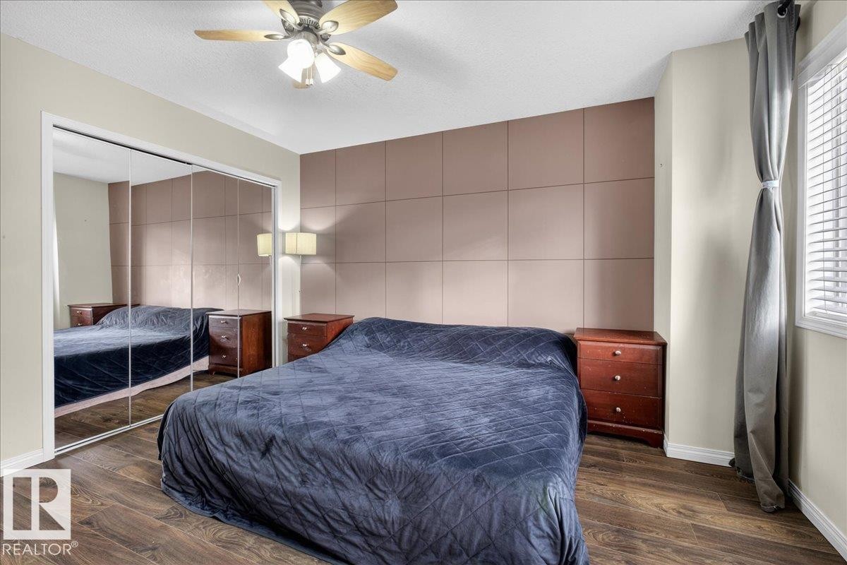 Bedroom with a ceiling fan, multiple windows, dark wood finished floors, a closet, and tile walls - 4519 Turner Square, Edmonton, AB - Indoor Photo Showing Bedroom