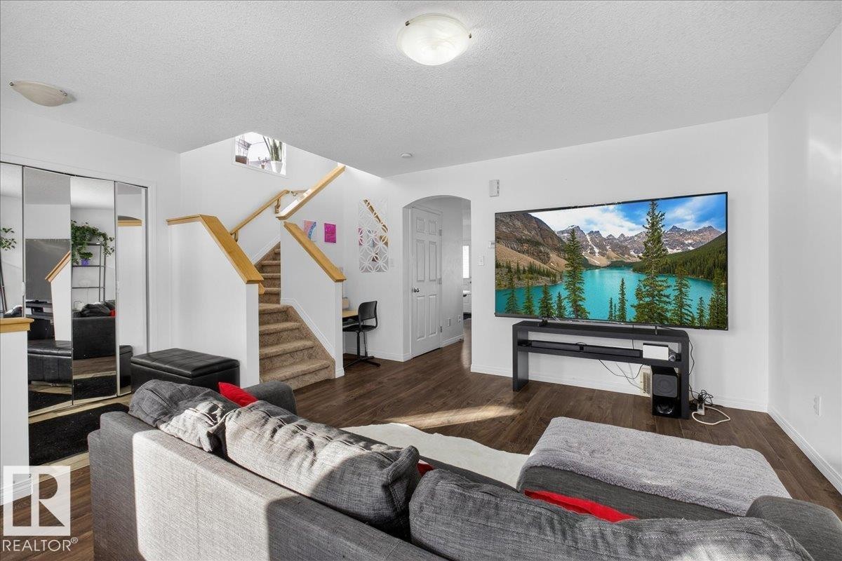 Living area featuring arched walkways, dark wood finished floors, and a textured ceiling - 4519 Turner Square, Edmonton, AB - Indoor Photo Showing Living Room