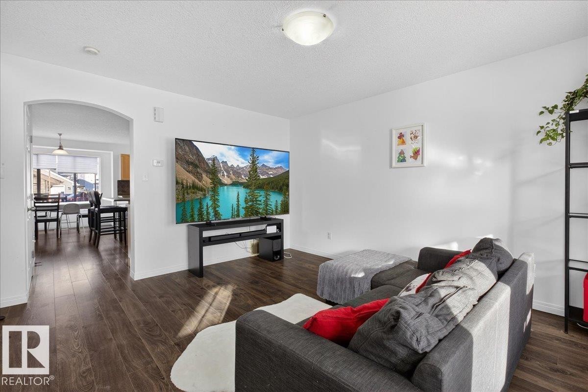 Living area featuring arched walkways, dark wood-style flooring, and a textured ceiling - 4519 Turner Square, Edmonton, AB - Indoor Photo Showing Living Room