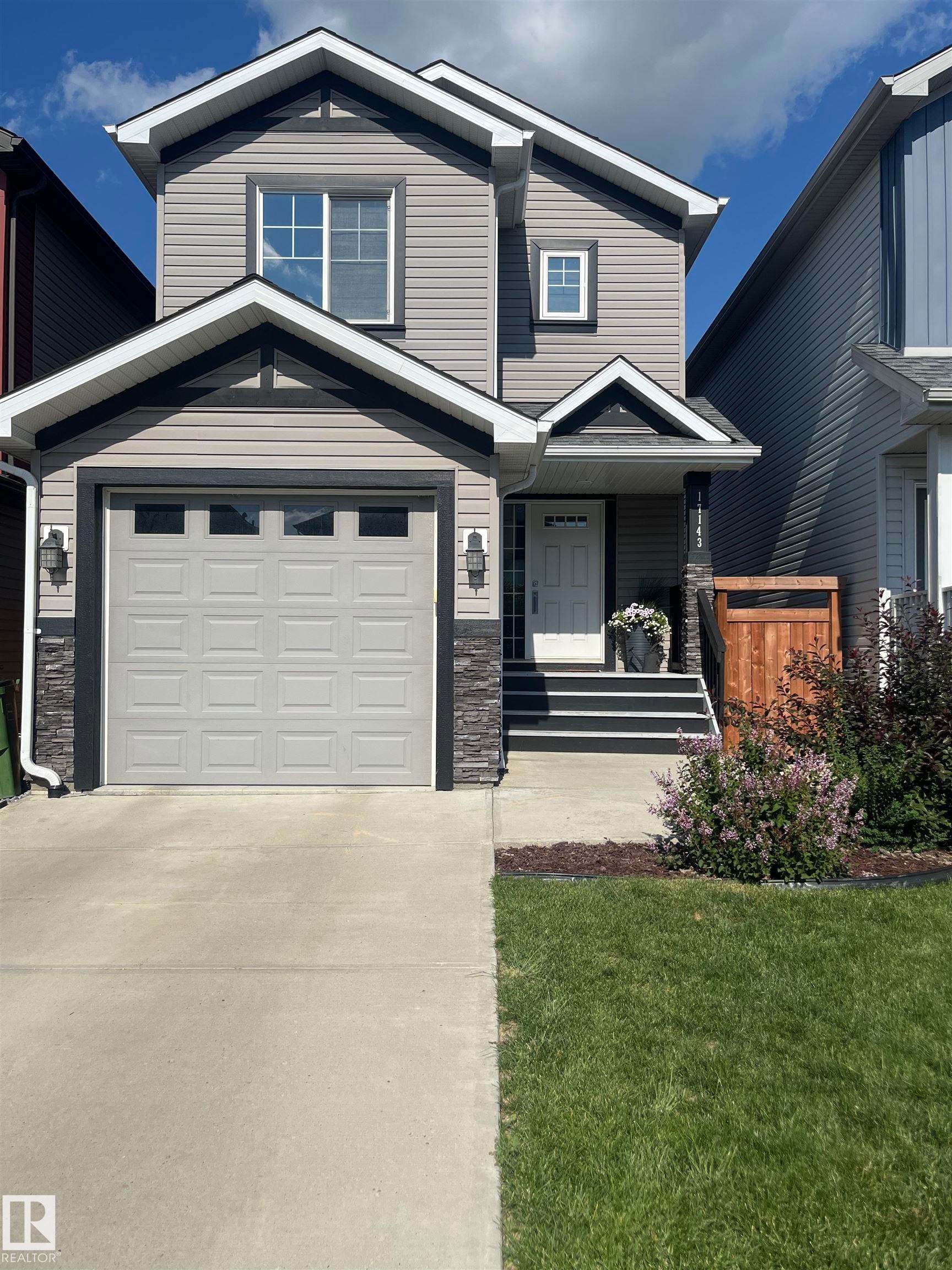 View of front of property with a porch, stone siding, concrete driveway, a front lawn, and an attached garage - 17143 38 Street, Edmonton, AB - Outdoor
