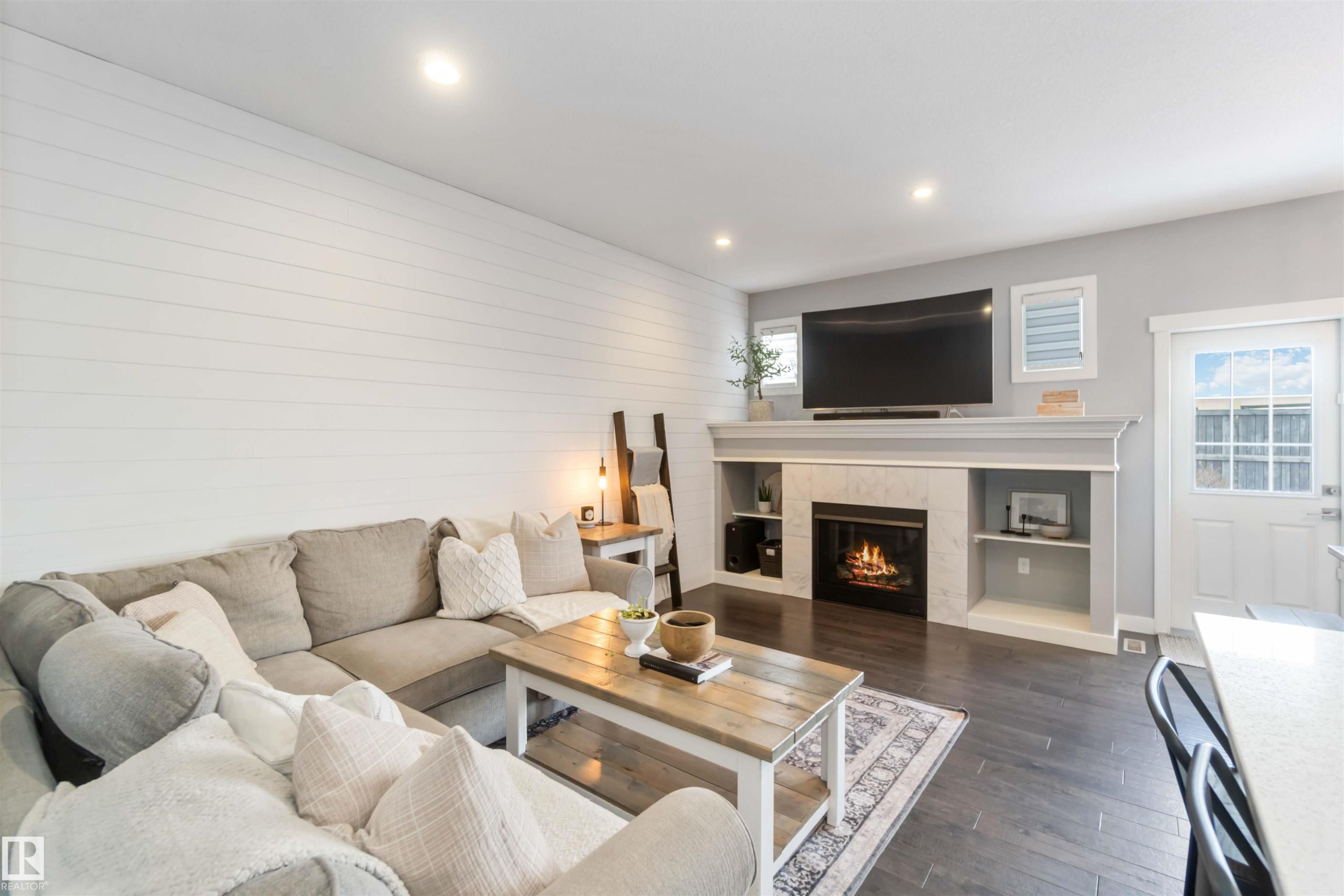Living area with dark wood finished floors, a tiled fireplace, and recessed lighting - 17143 38 Street, Edmonton, AB - Indoor Photo Showing Living Room With Fireplace