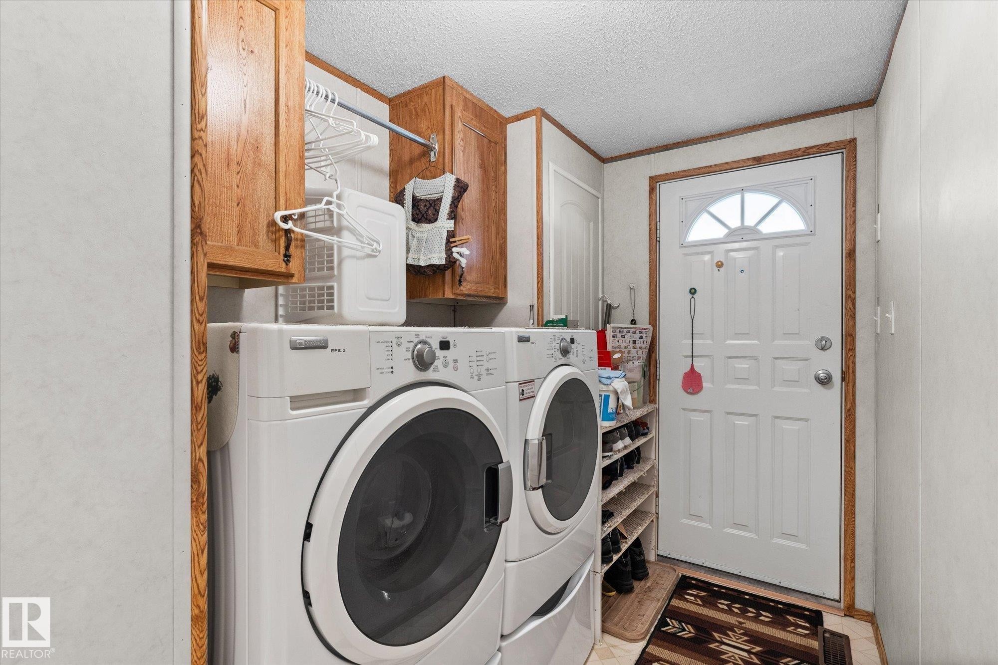 Laundry area with a textured ceiling, separate washer and dryer, cabinet space, and crown molding - 89-3400 48, Stony Plain, AB - Indoor Photo Showing Laundry Room