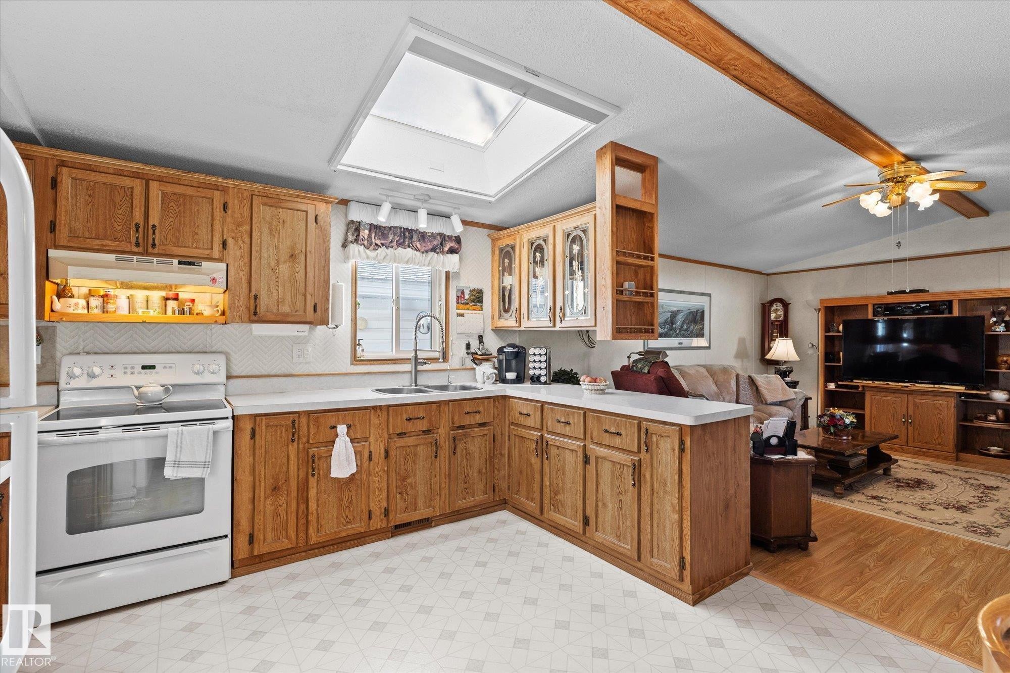 Kitchen with white electric range oven, light floors, glass insert cabinets, light countertops, and lofted ceiling with beams - 89-3400 48, Stony Plain, AB - Indoor Photo Showing Kitchen With Double Sink