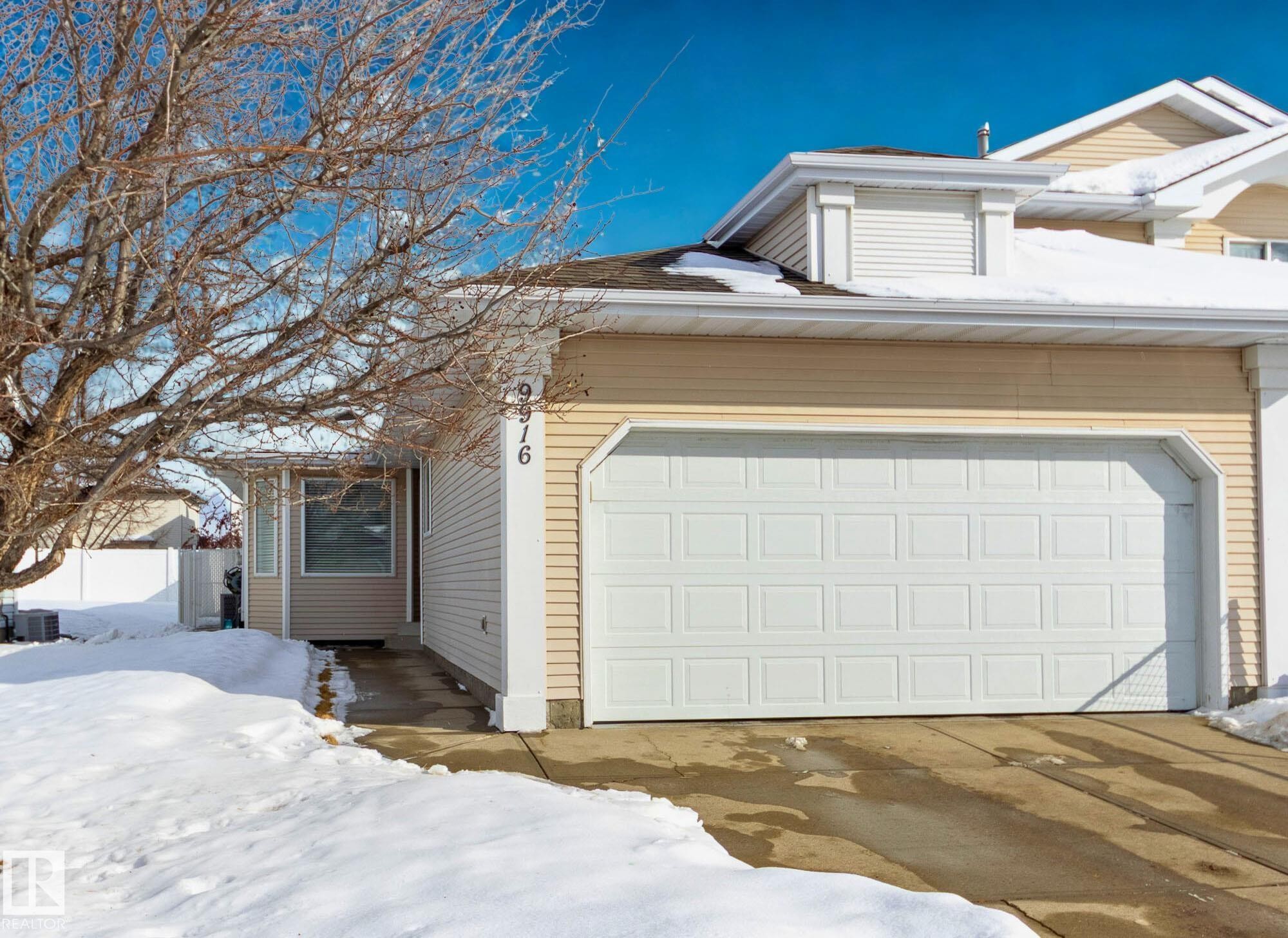 The property features a spacious two-car garage with a white panel door, complemented by light-toned siding - 9916 178 Avenue, Edmonton, AB - Outdoor