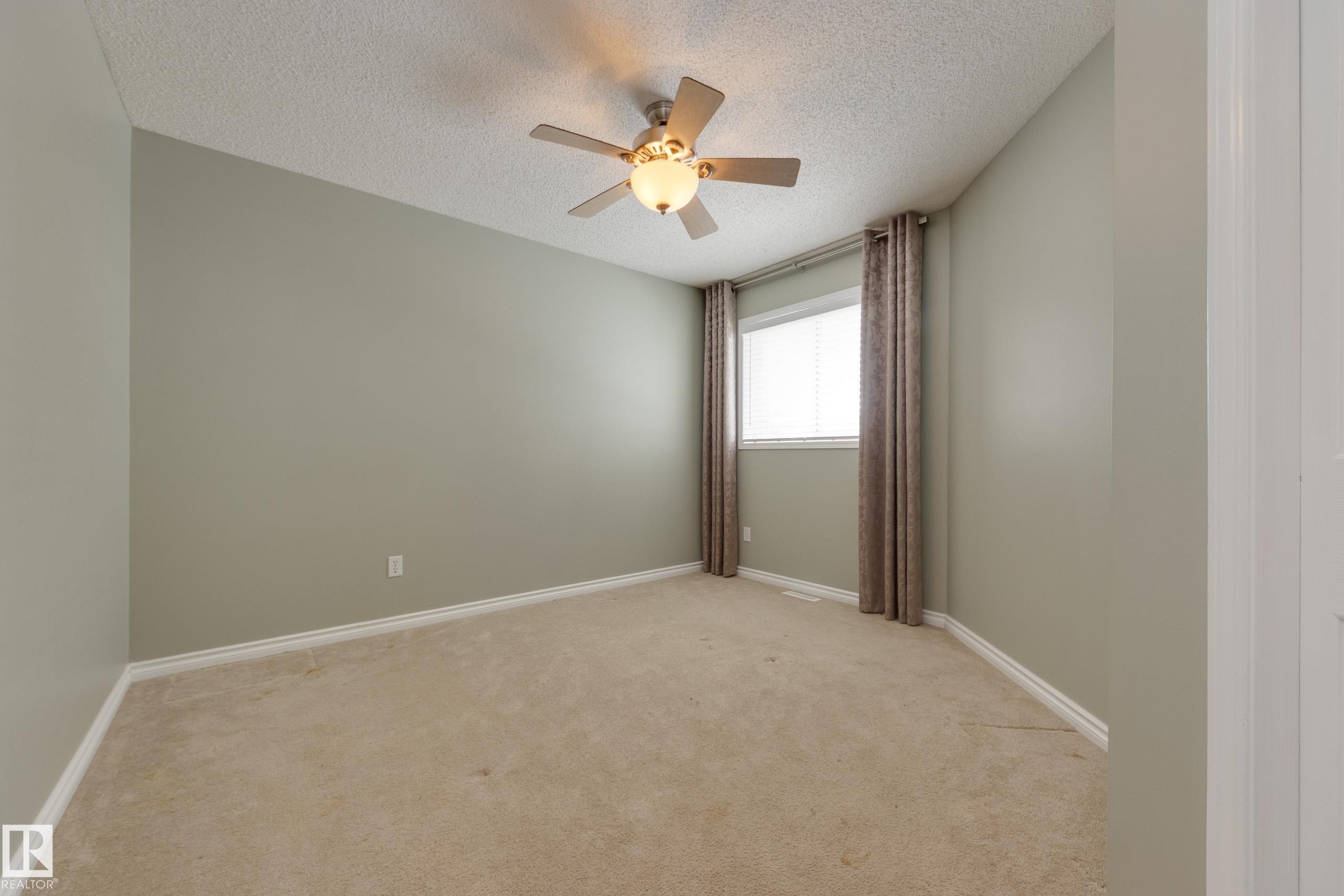 Unfurnished room featuring a textured ceiling, light carpet, and ceiling fan - 9916 178 Avenue, Edmonton, AB - Indoor Photo Showing Other Room