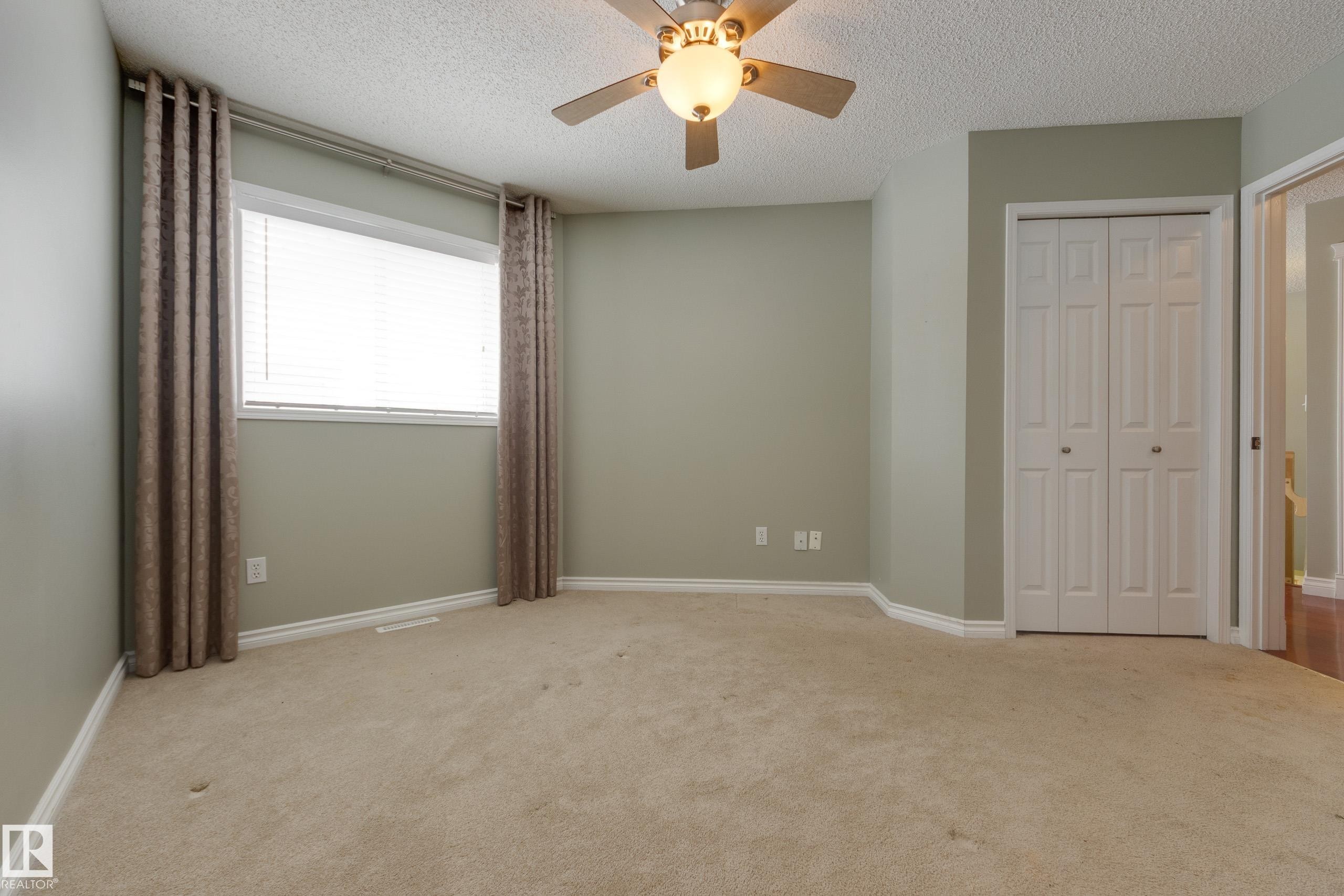 Unfurnished bedroom featuring light carpet, ceiling fan, a closet, and a textured ceiling - 9916 178 Avenue, Edmonton, AB - Indoor