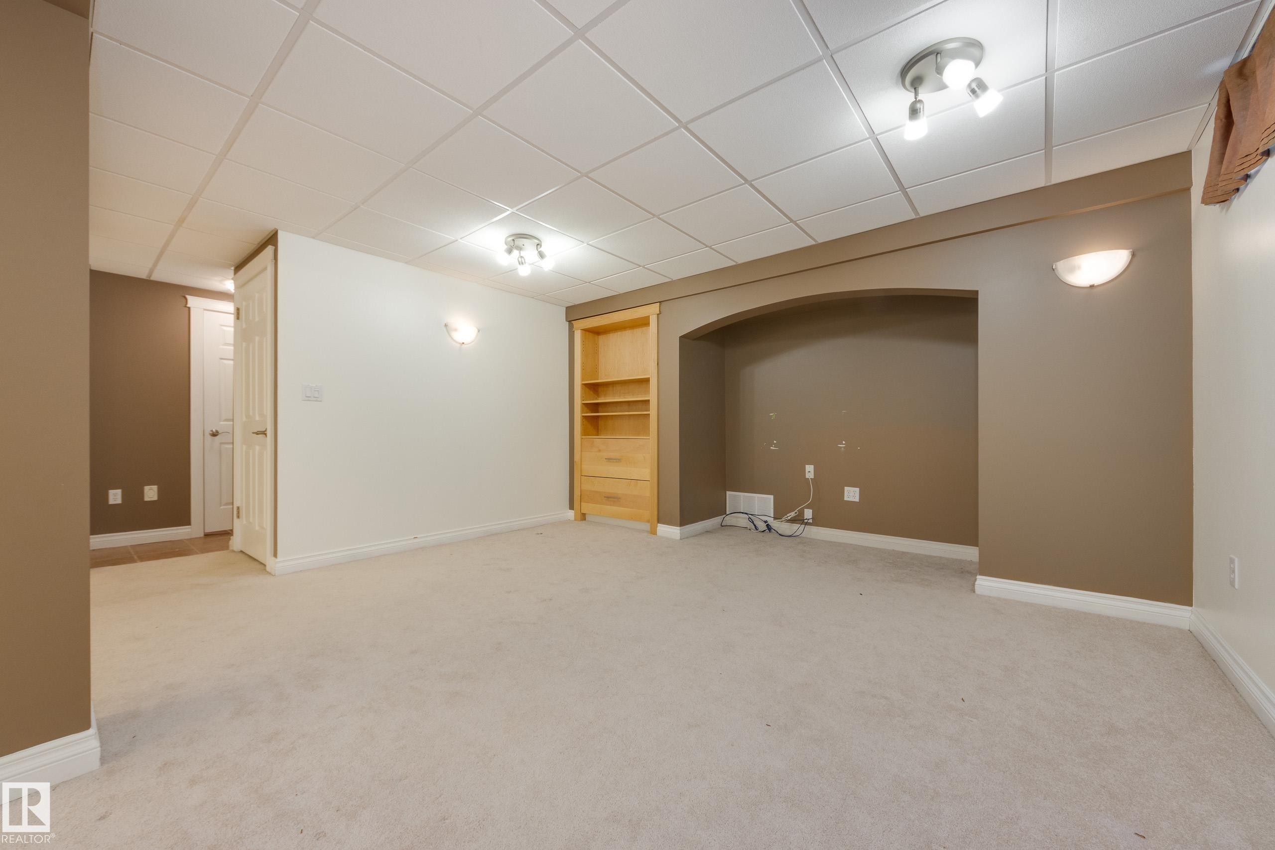 Finished basement with built in shelves, a drop ceiling, and light colored carpet - 9916 178 Avenue, Edmonton, AB - Indoor
