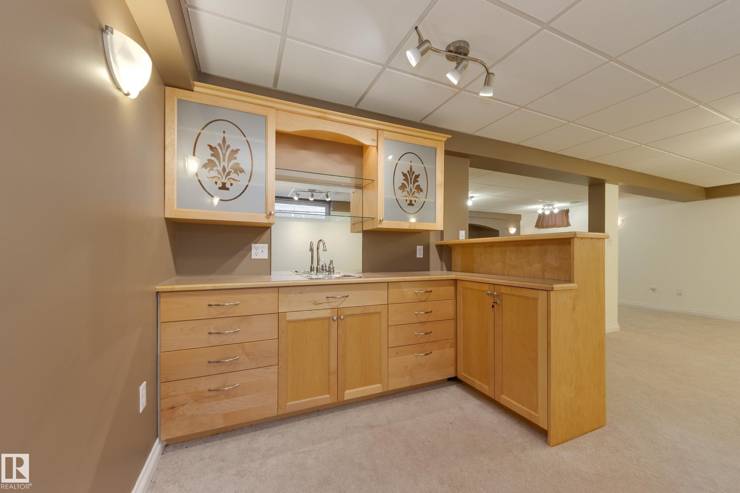 Kitchen featuring a paneled ceiling, light wood finish cabinetry, a peninsula, light countertops, and light colored carpet - 9916 178 Avenue, Edmonton, AB - Indoor