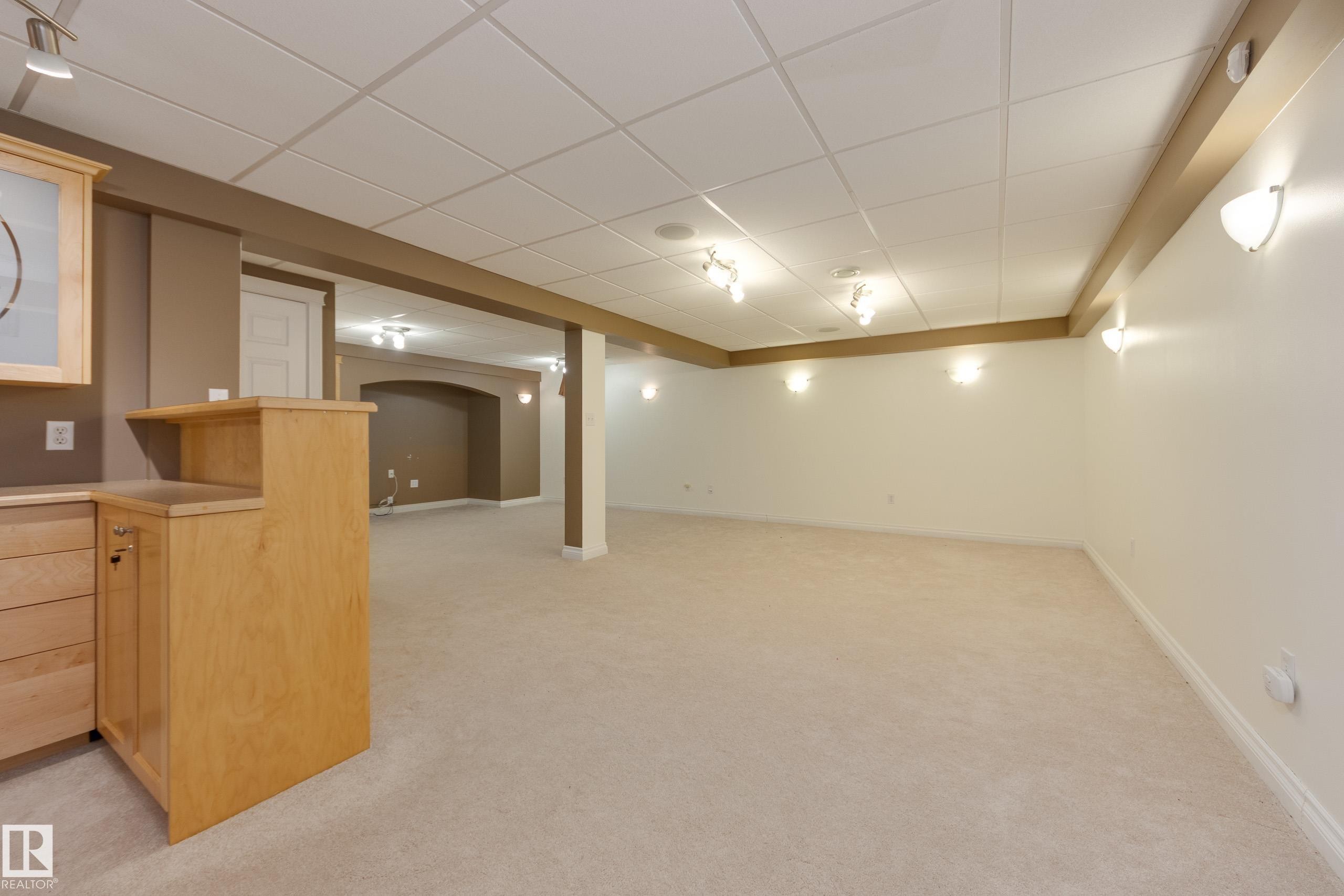 Finished below grade area featuring a paneled ceiling, light carpet, and arched walkways - 9916 178 Avenue, Edmonton, AB - Indoor