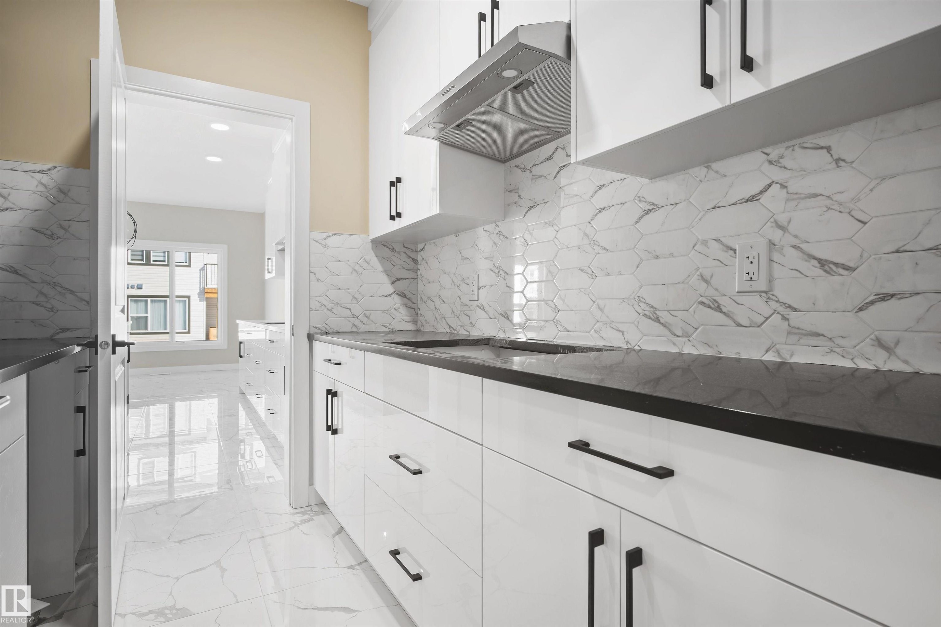 Kitchen featuring ventilation hood, white cabinetry, light marble finish floors, recessed lighting, and dark stone countertops - 3910 41 Avenue, Beaumont, AB - Indoor Photo Showing Kitchen
