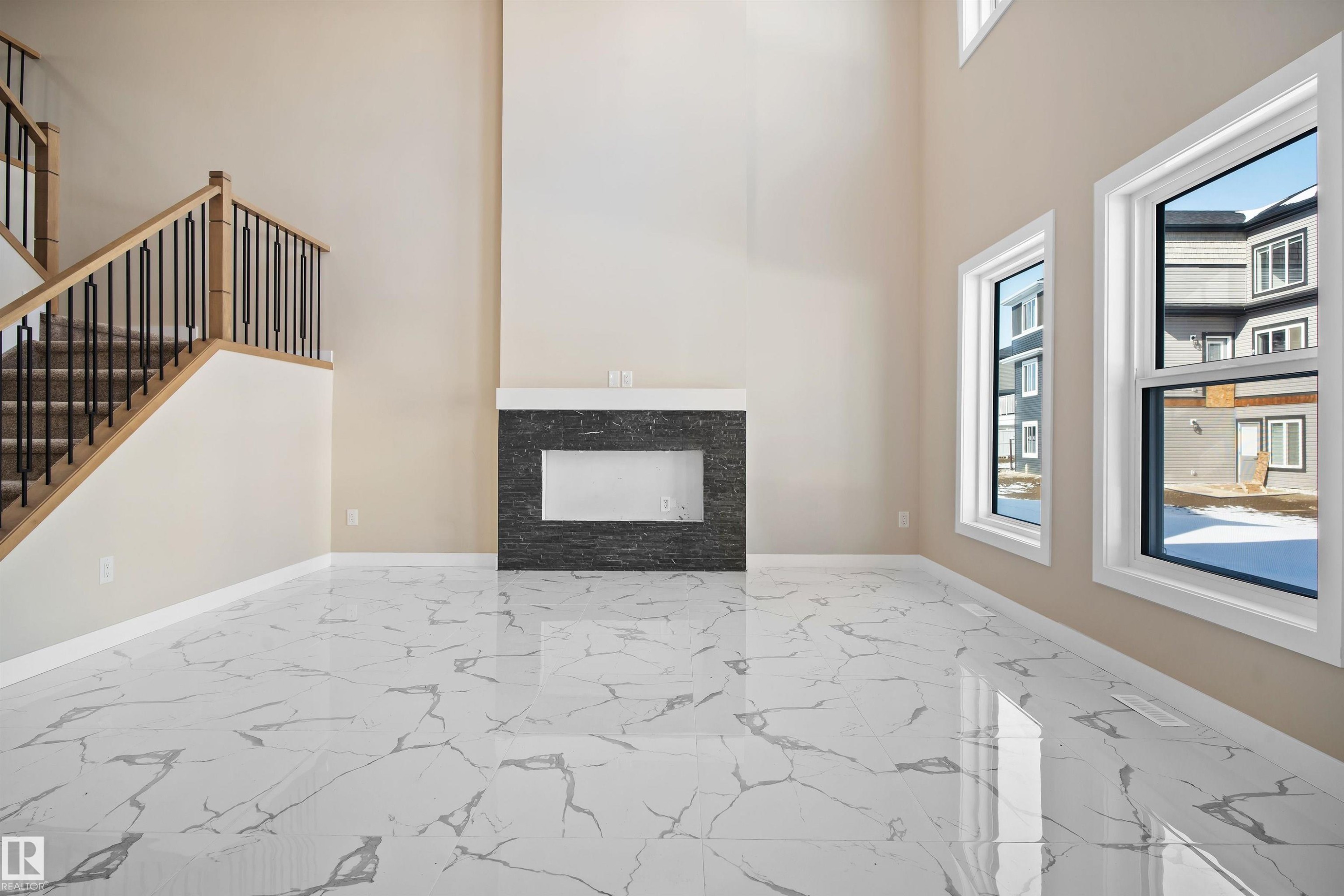 Unfurnished living room featuring a fireplace, light marble finish flooring, and a high ceiling - 3910 41 Avenue, Beaumont, AB - Indoor Photo Showing Other Room With Fireplace
