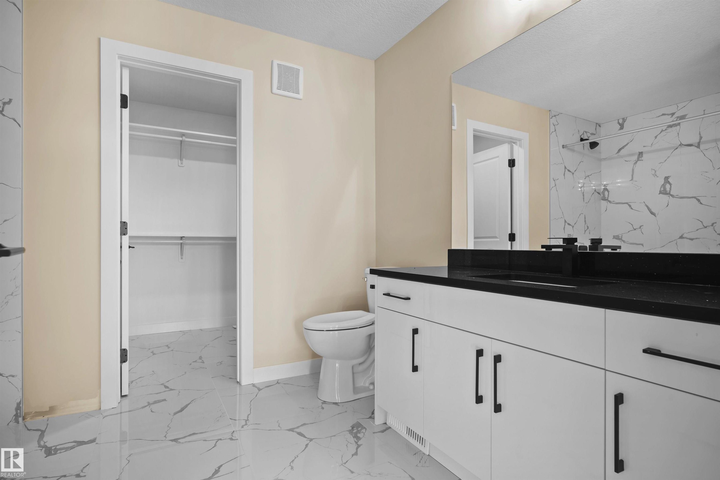 Full bathroom featuring vanity, light marble finish flooring, a marble finish shower, a spacious closet, and a textured ceiling - 3910 41 Avenue, Beaumont, AB - Indoor Photo Showing Bathroom