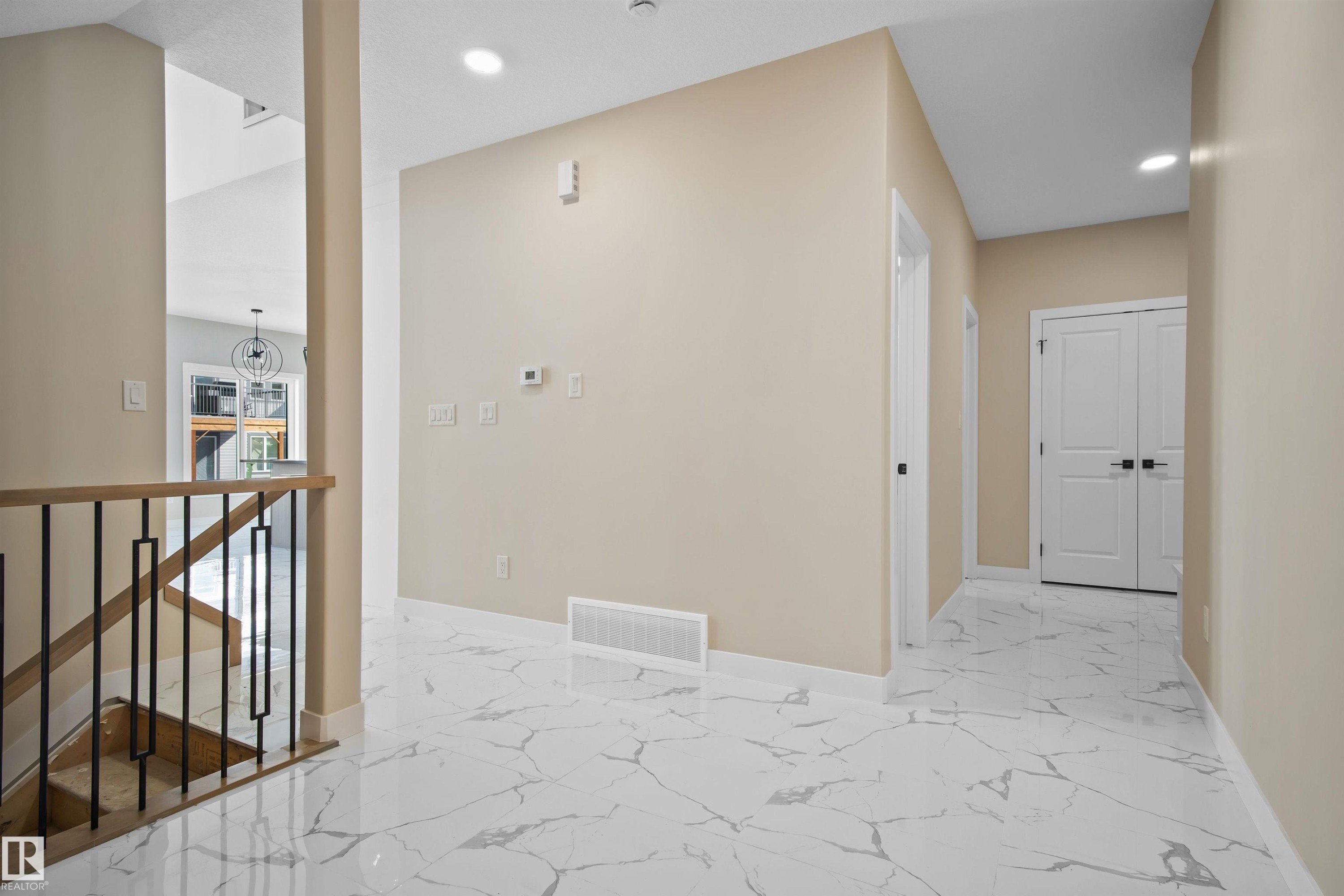 Corridor with light marble finish floors, an upstairs landing, and suspended lighting - 3910 41 Avenue, Beaumont, AB - Indoor Photo Showing Other Room
