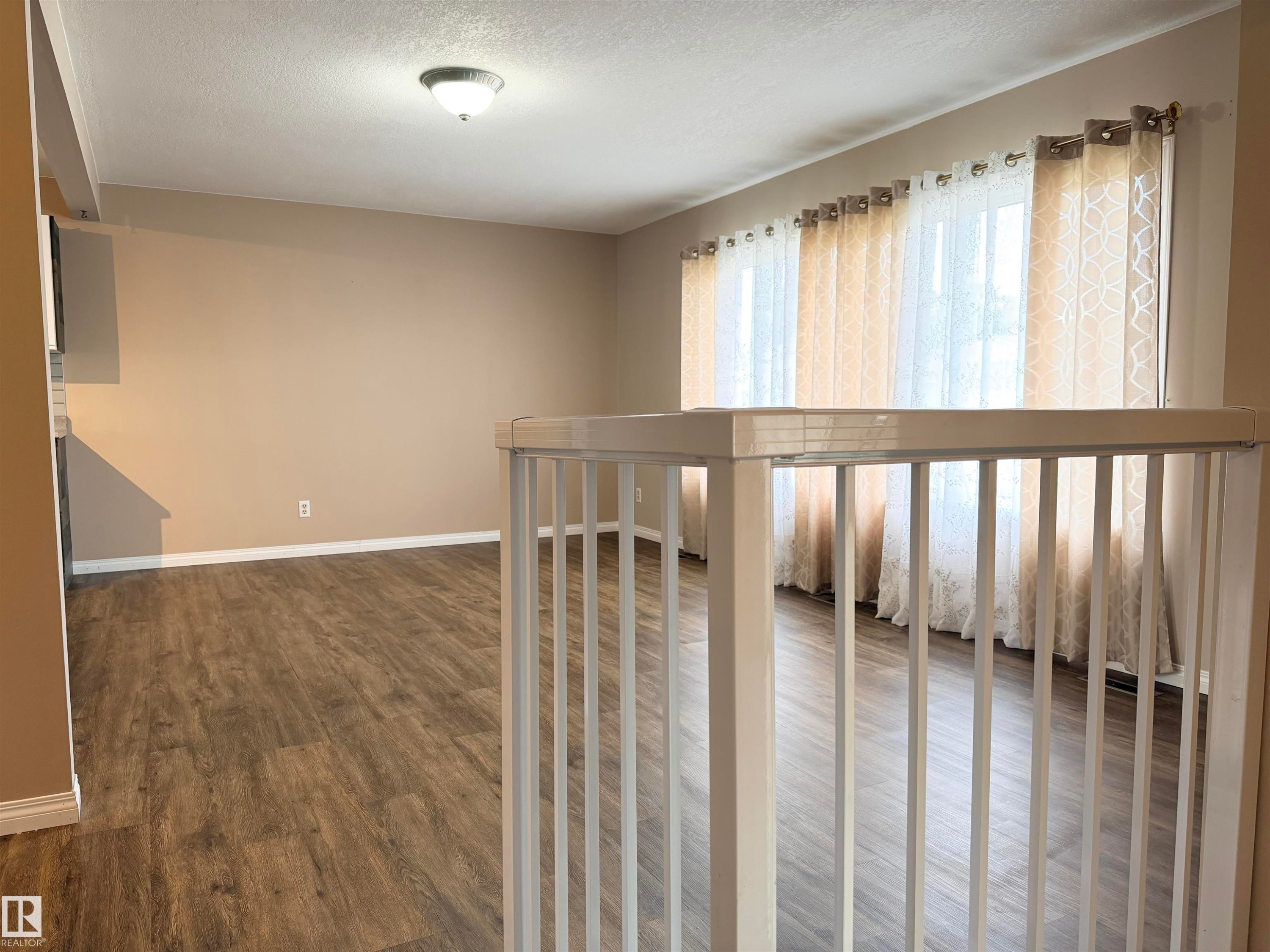 Wood-finish flooring, neutral wall tones, semi-flush ceiling light fixture - 10503 110 Street, Westlock, AB