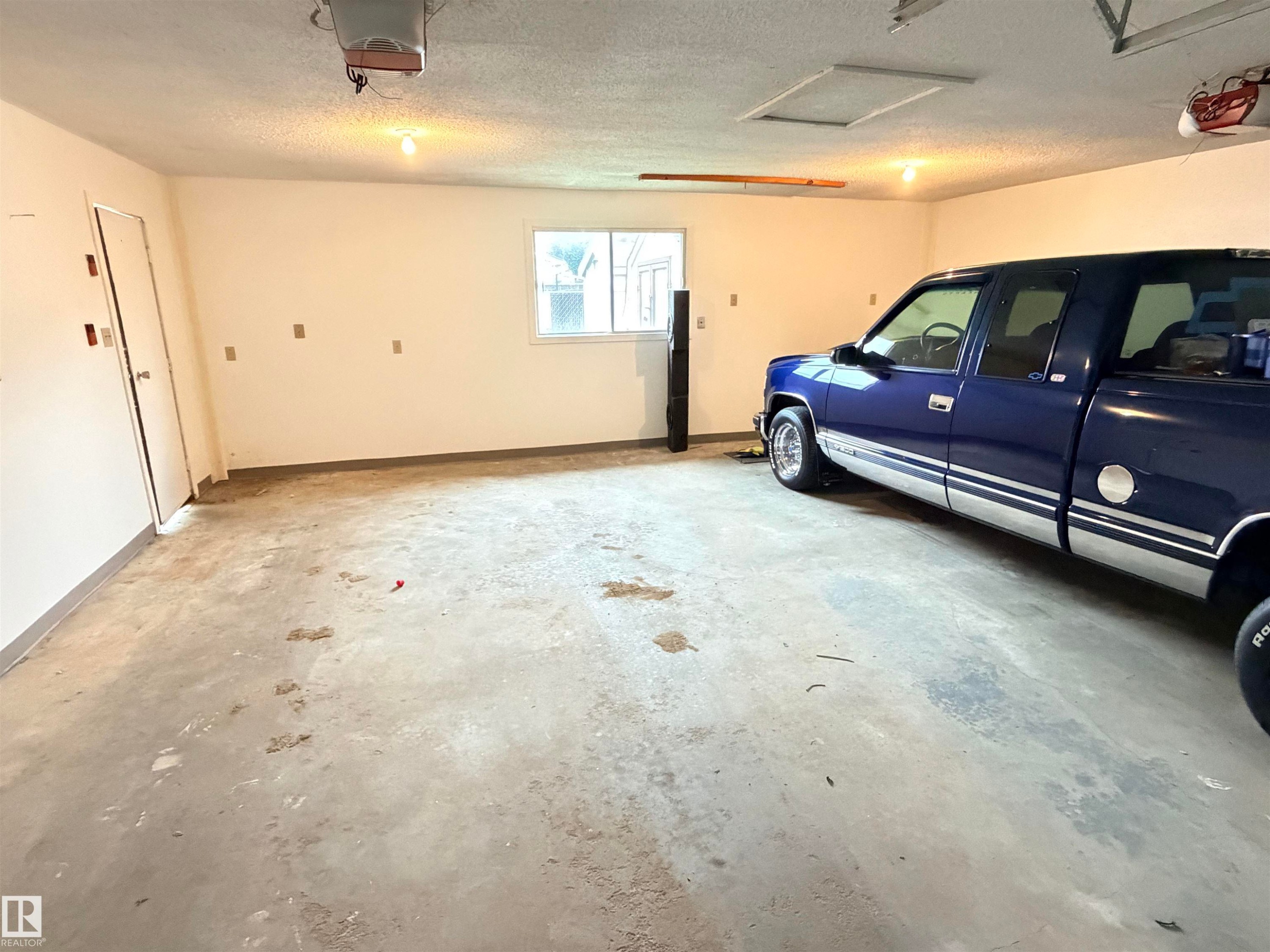 Attached garage with a concrete floor, painted walls, and overhead lighting - 10503 110 Street, Westlock, AB