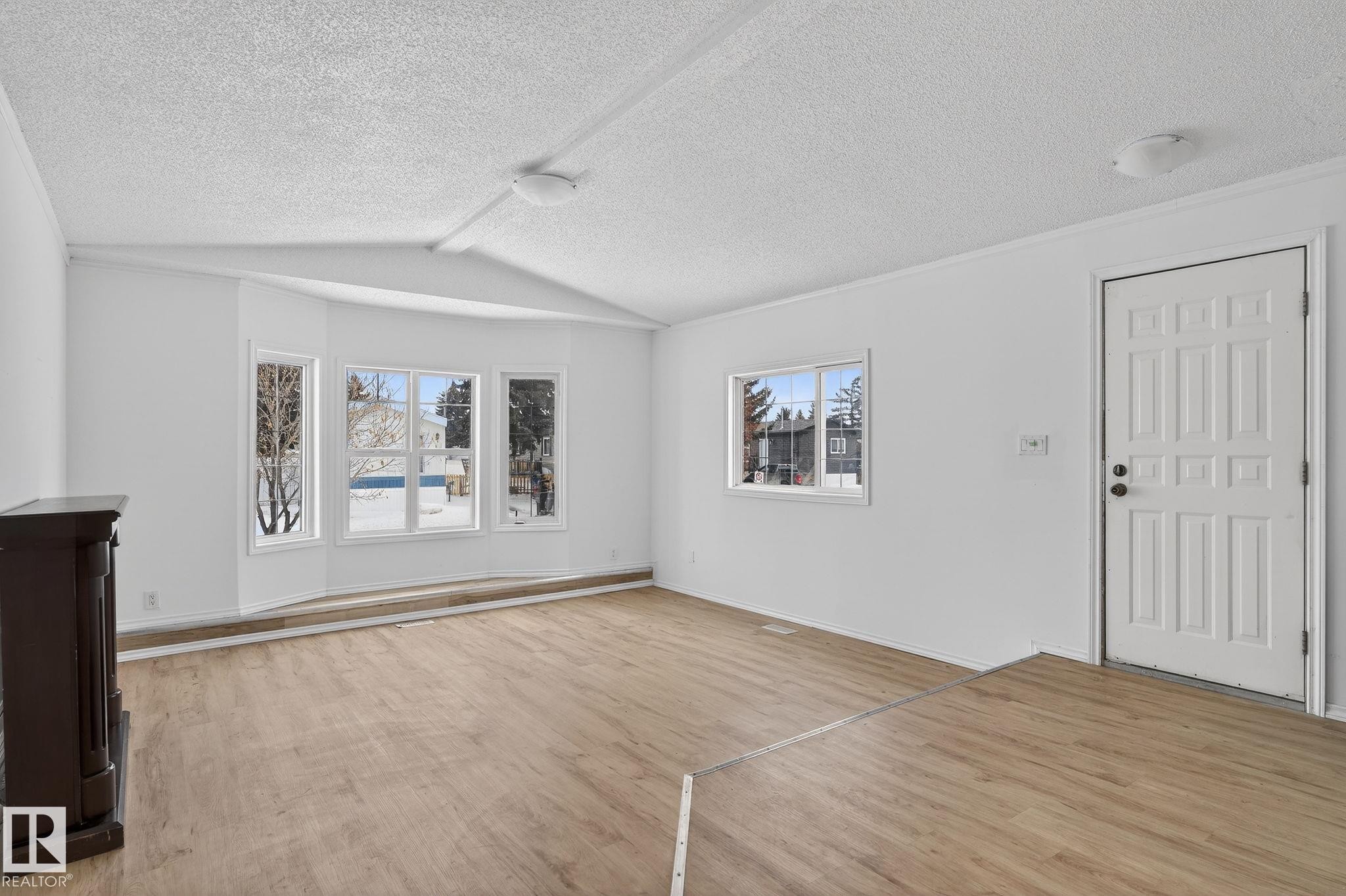 Unfurnished living room with light wood-type flooring and a textured ceiling - 72 Evergreen Park, Edmonton, AB - Indoor