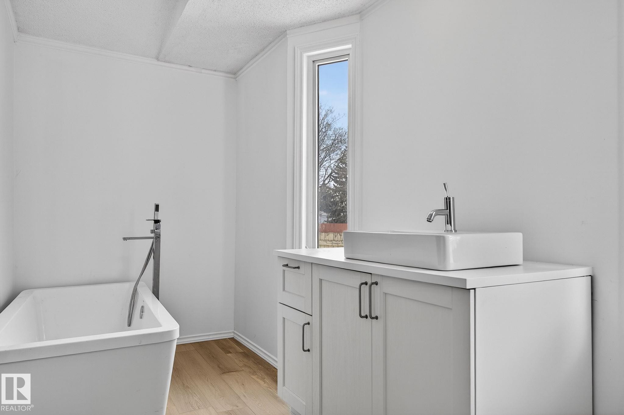 Laundry area with a textured ceiling, light wood-type flooring, and crown molding - 72 Evergreen Park, Edmonton, AB - Indoor Photo Showing Laundry Room