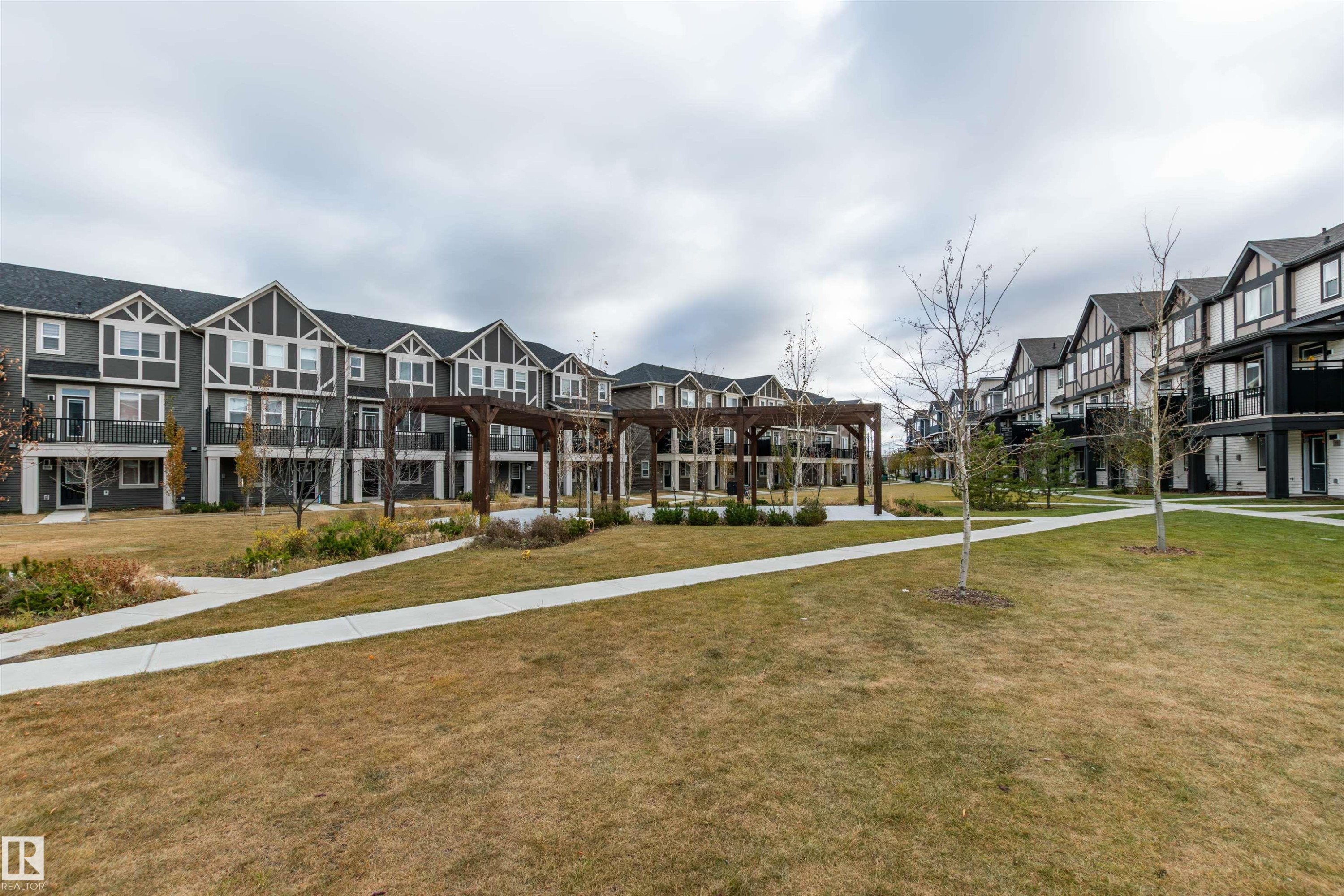 Surrounding community with a yard and a residential view - 105 2072 Wonnacott Way, Edmonton, AB - Outdoor With Facade