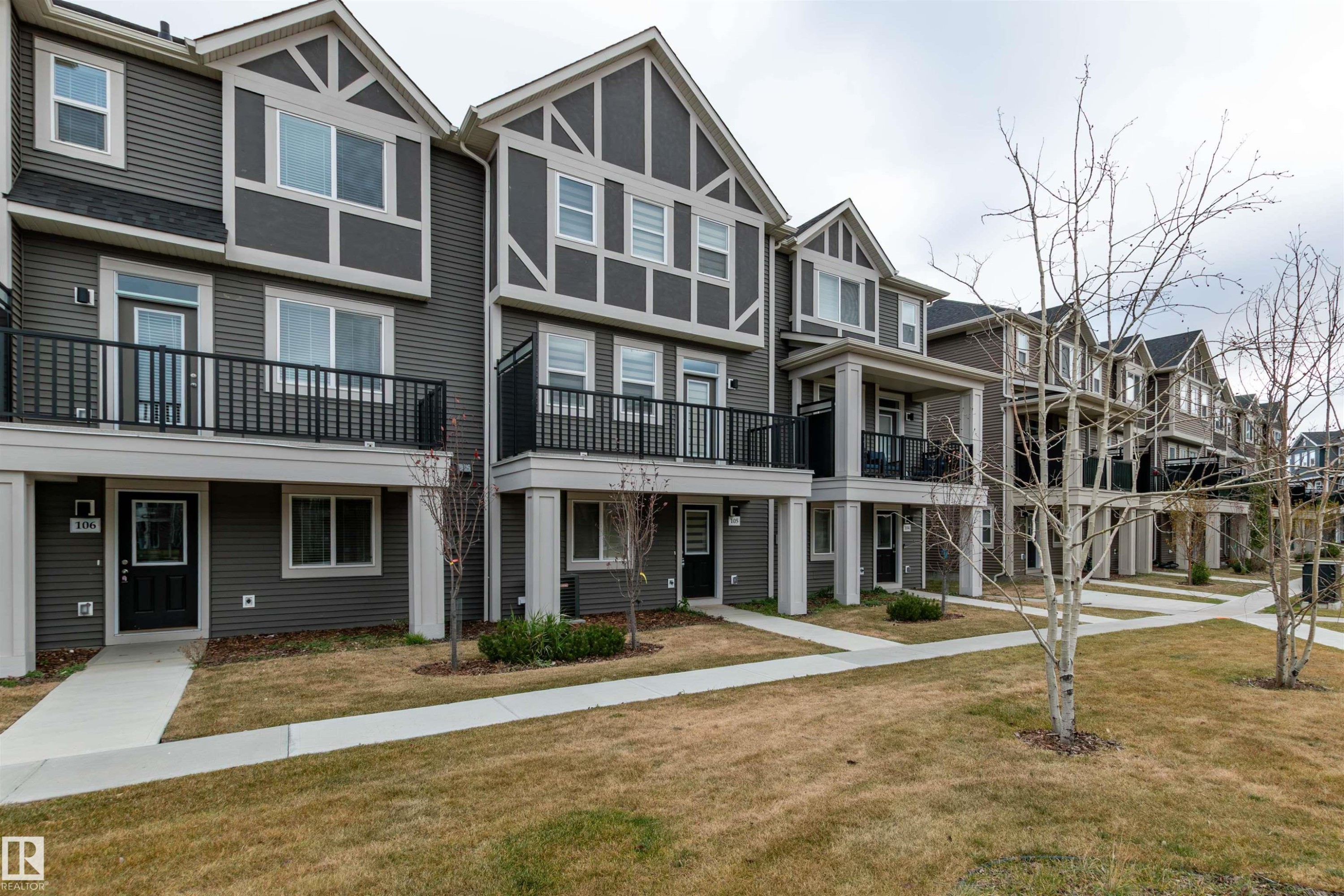 View of front of house with a front yard, a residential view, and a balcony - 105 2072 Wonnacott Way, Edmonton, AB - Outdoor With Facade