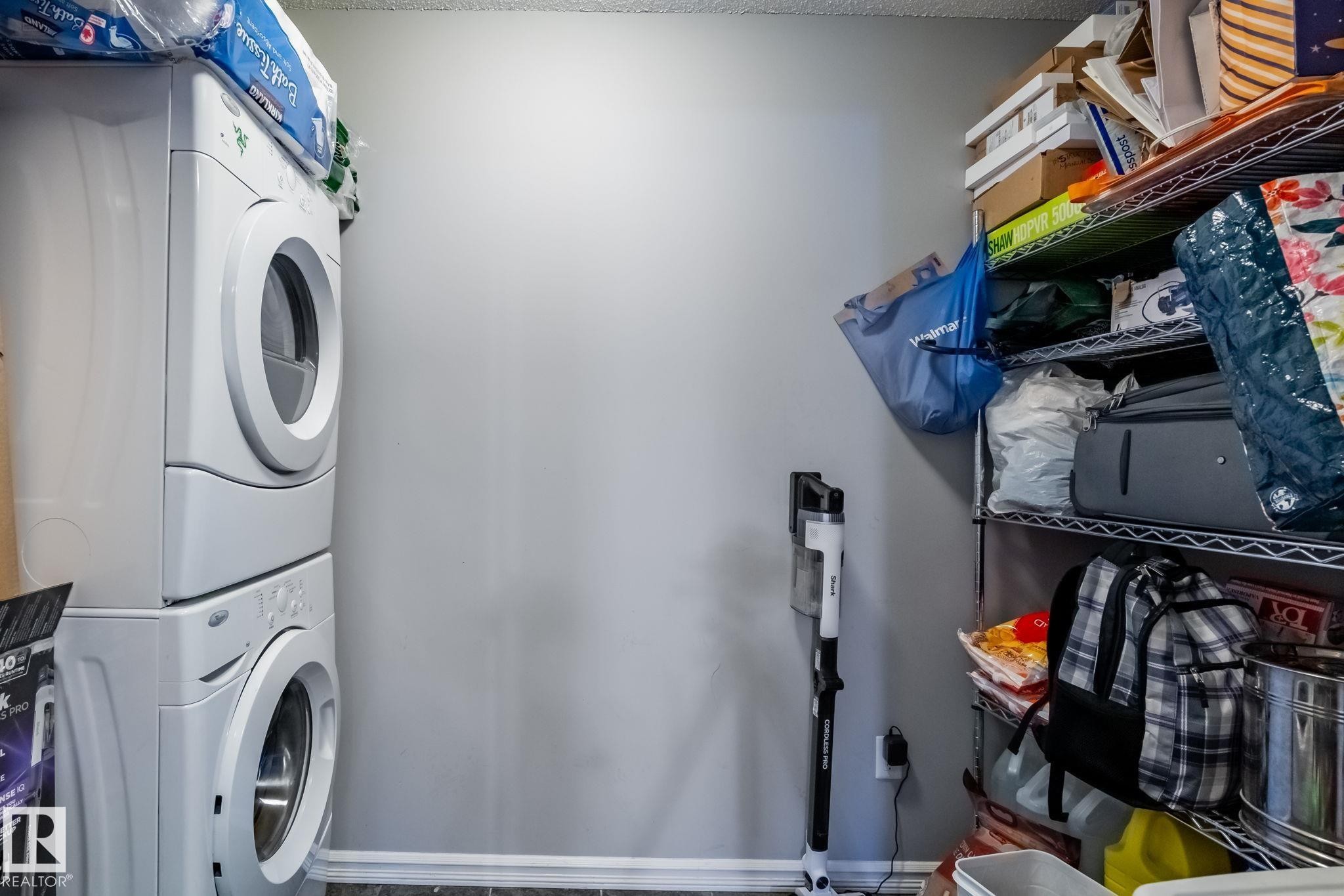Laundry area with stacked washing machine and dryer and baseboards - 207 2203 44 Avenue, Edmonton, AB - Indoor Photo Showing Laundry Room