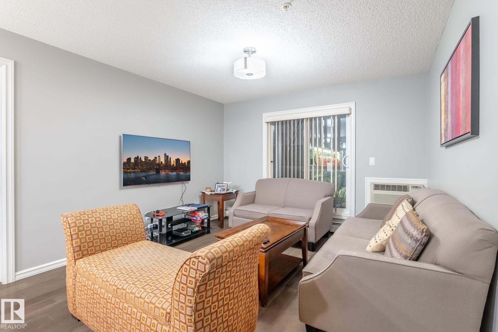 Living area with wood finished floors and a textured ceiling - 207 2203 44 Avenue, Edmonton, AB - Indoor Photo Showing Other Room