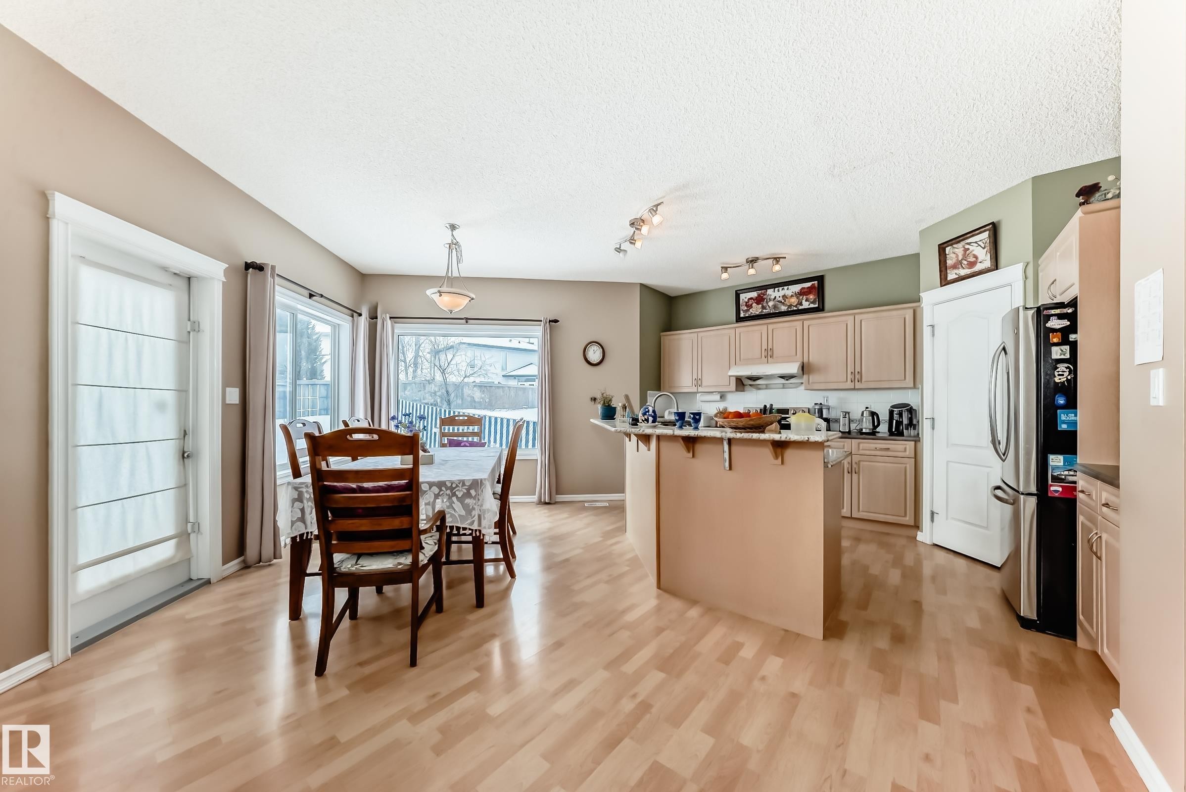 Kitchen featuring a kitchen breakfast bar, freestanding refrigerator, light wood-style floors, light wood finish cabinets, and a center island with sink - 4619 151 Avenue, Edmonton, AB - Indoor