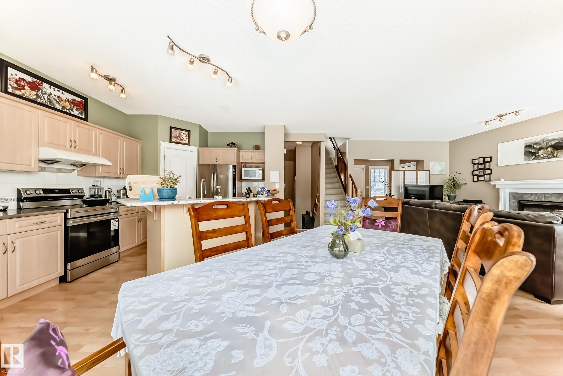 Dining area featuring track lighting, light wood-type flooring, and a premium fireplace - 4619 151 Avenue, Edmonton, AB - Indoor