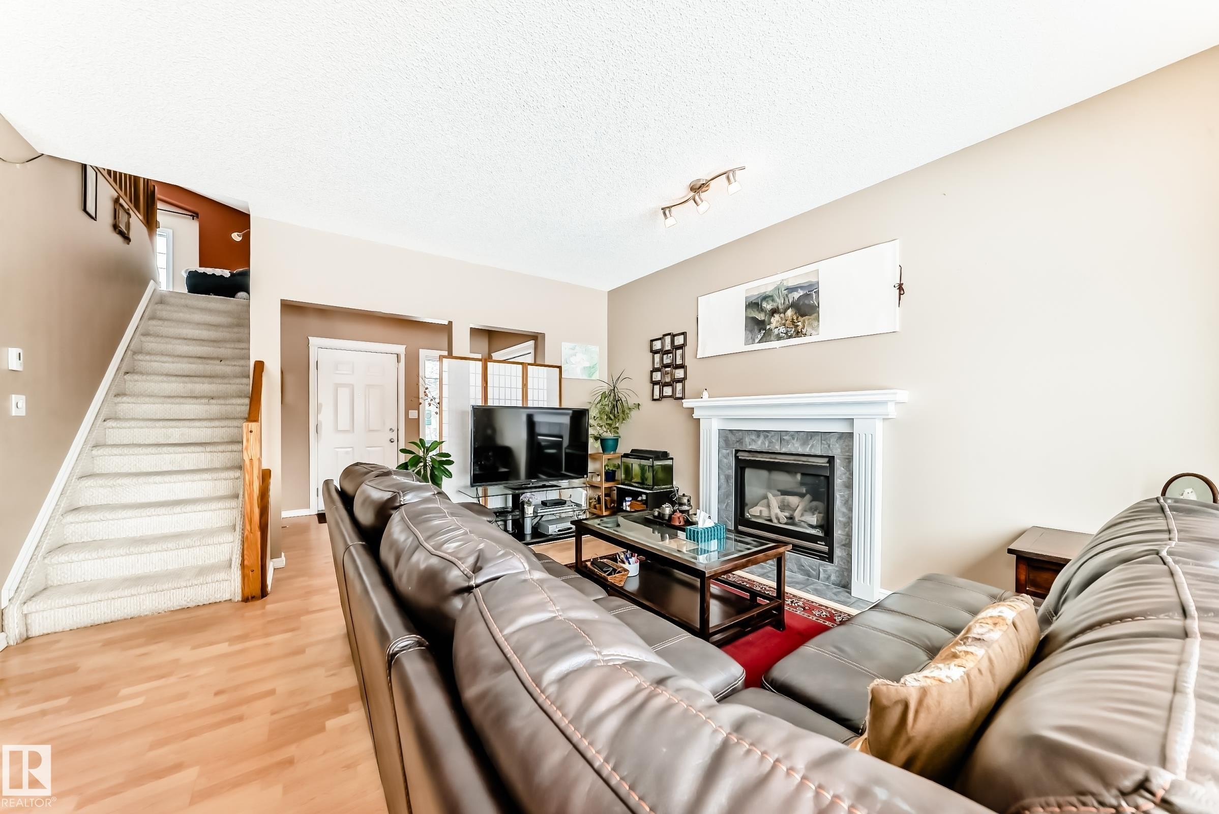 Living room with a fireplace, wood finished floors, plenty of natural light, and a textured ceiling - 4619 151 Avenue, Edmonton, AB - Indoor Photo Showing Living Room With Fireplace