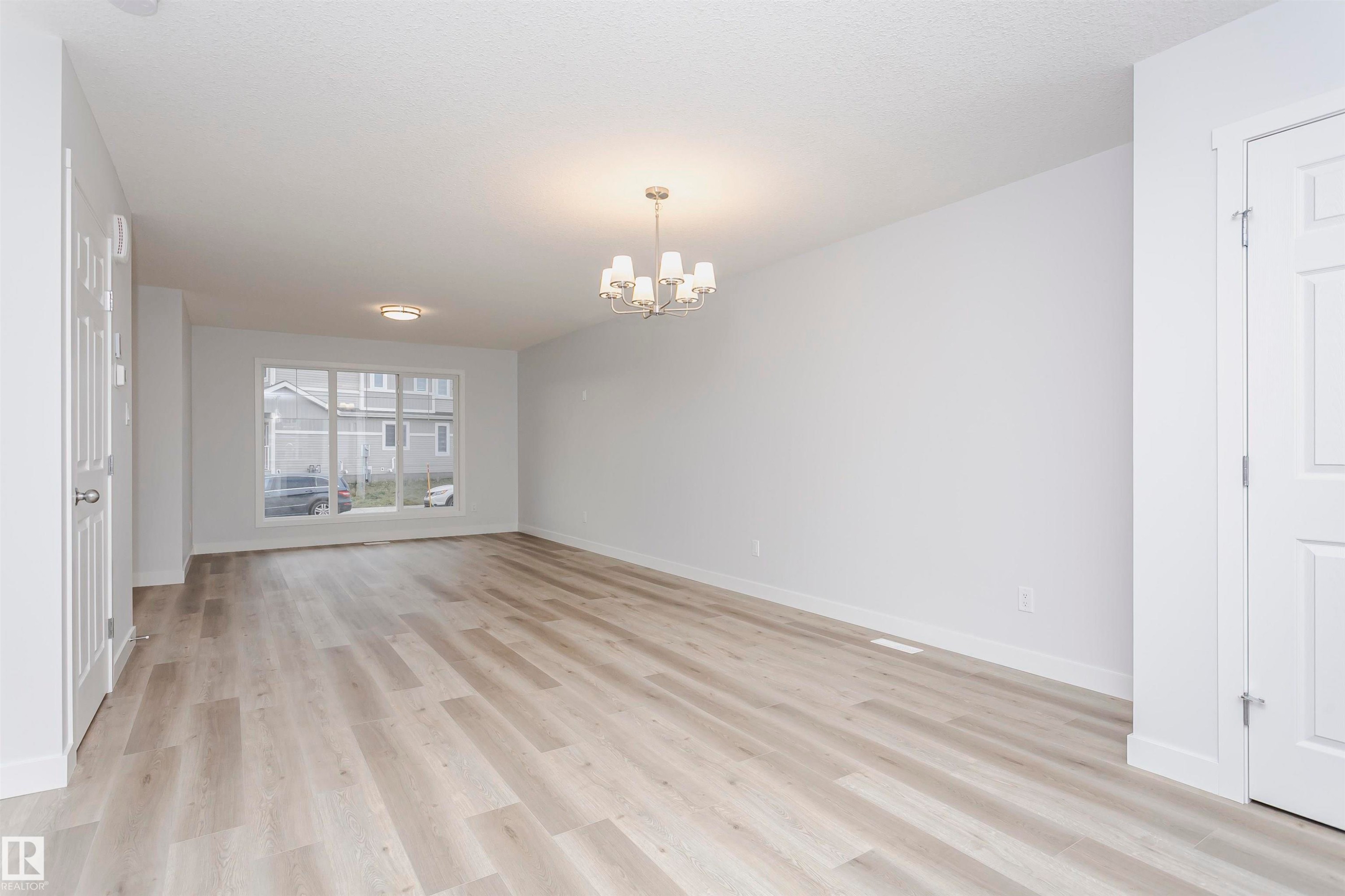 Empty room with light wood-type flooring and a chandelier - 9564 Carson Bend, Edmonton, AB - Indoor