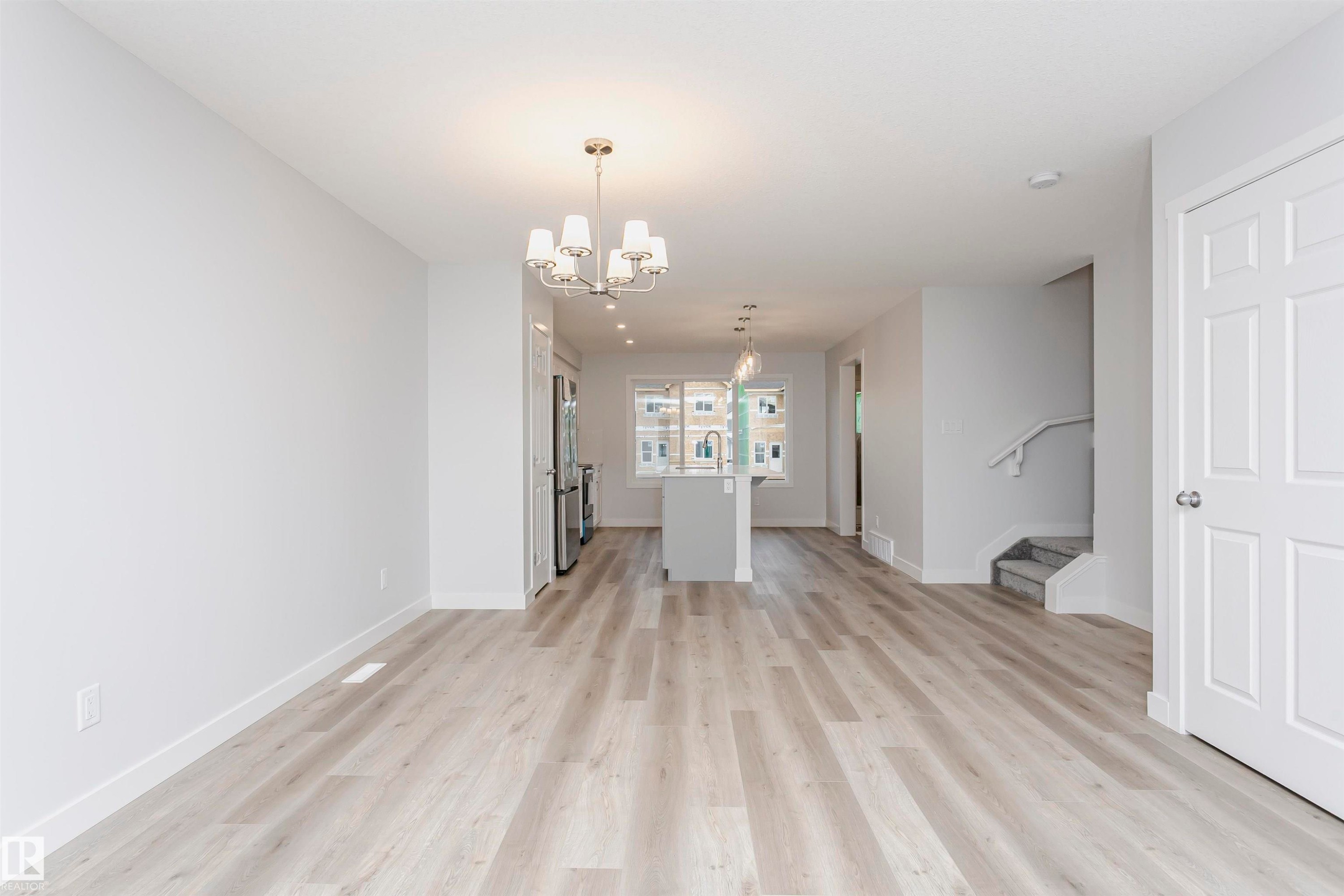 Unfurnished living room with light wood-style flooring and a chandelier - 9564 Carson Bend, Edmonton, AB - Indoor Photo Showing Other Room