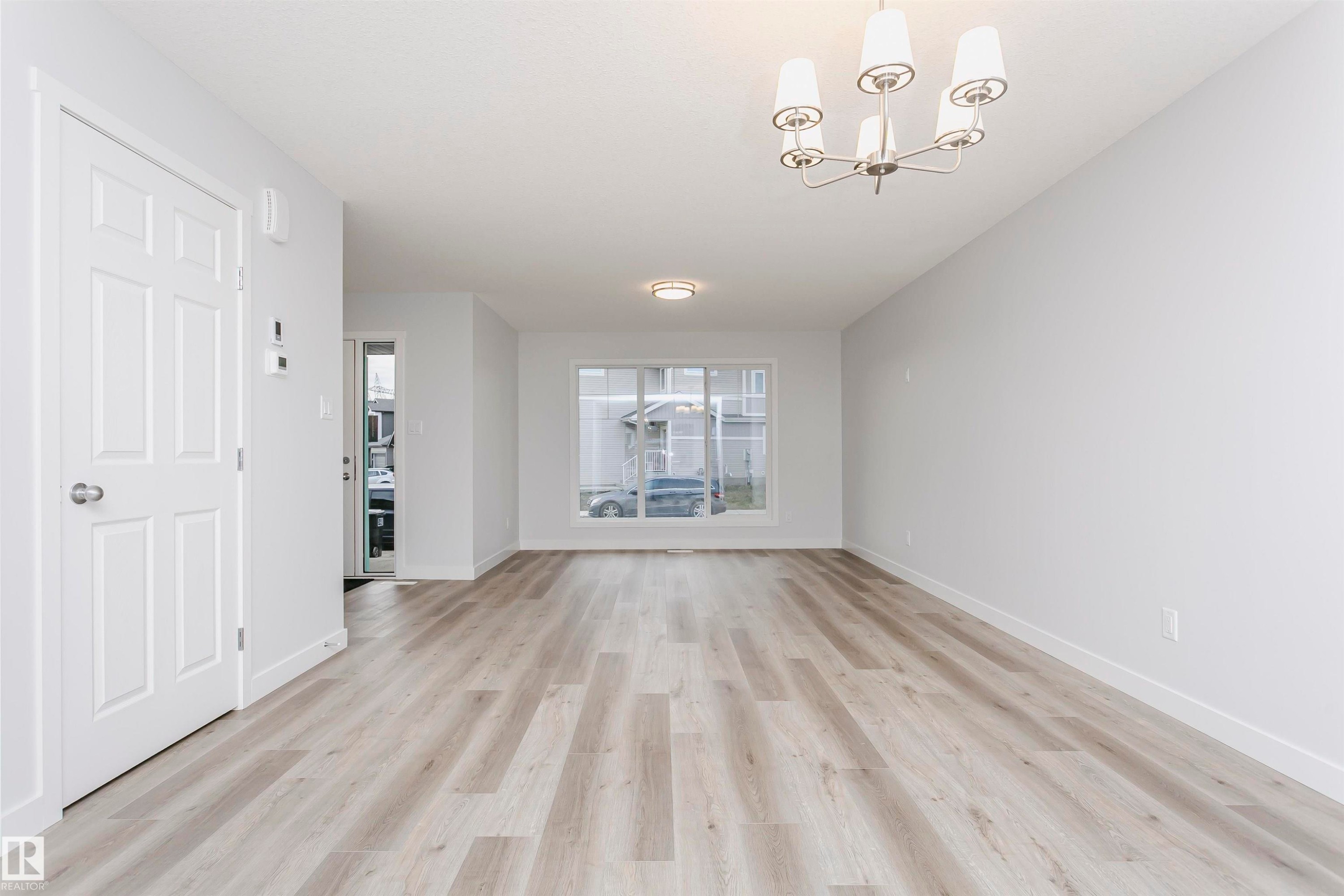 Unfurnished living room featuring light wood-type flooring and suspended lighting - 9564 Carson Bend, Edmonton, AB - Indoor Photo Showing Other Room