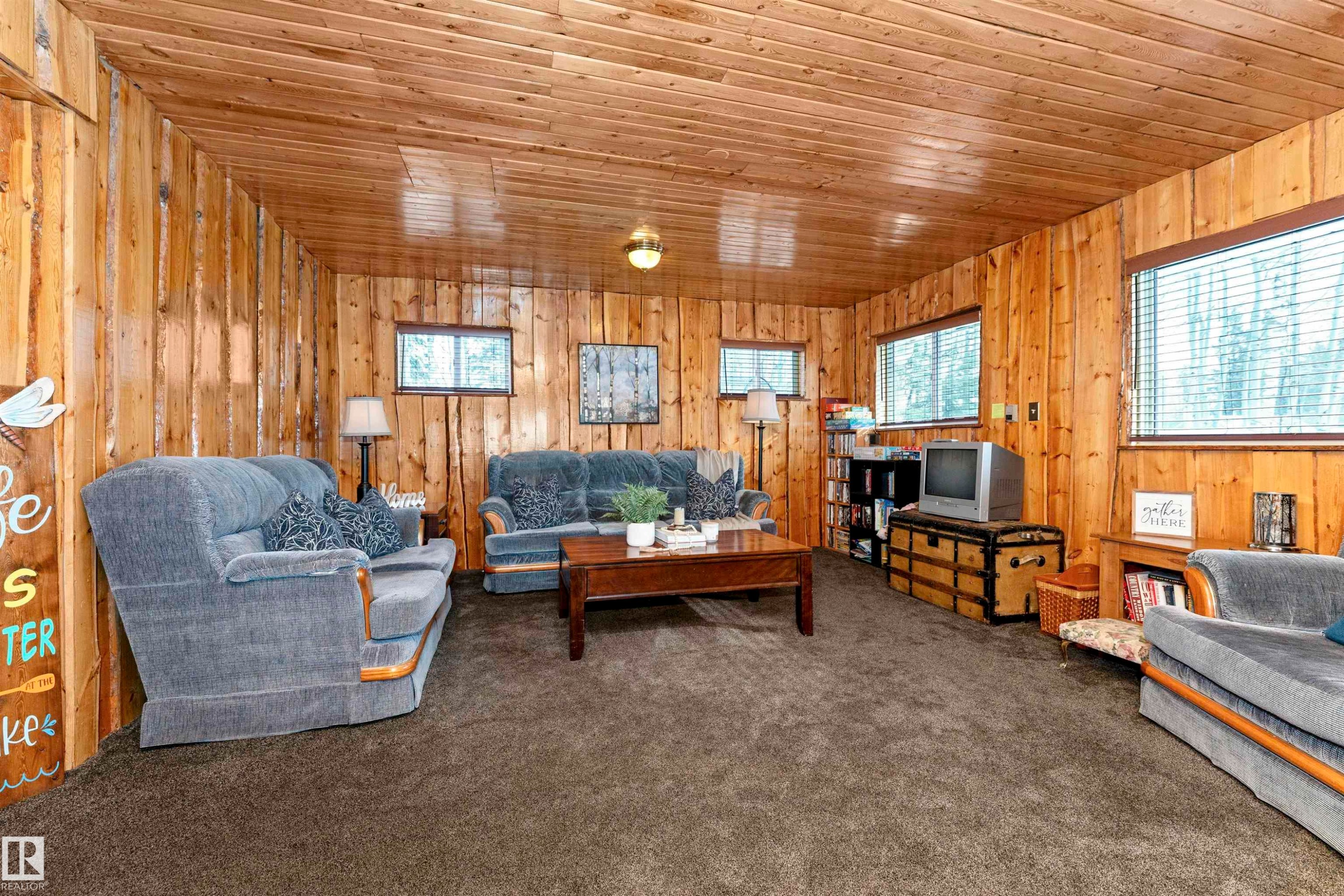 Living room featuring wood walls, carpet flooring, a stone fireplace, and wood ceiling - 516 5 Street, Rural Lac Ste. Anne County, AB - Indoor Photo Showing Living Room With Fireplace