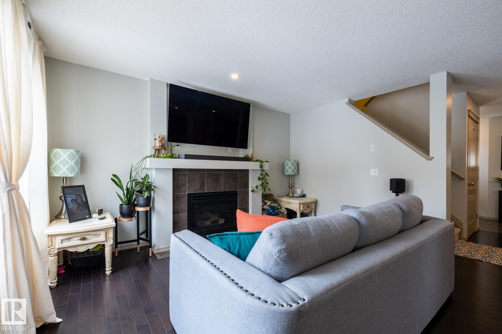 Living room featuring dark wood-style flooring, a textured ceiling, a tiled fireplace, and recessed lighting - 3312 17B Avenue, Edmonton, AB - Indoor Photo Showing Living Room With Fireplace