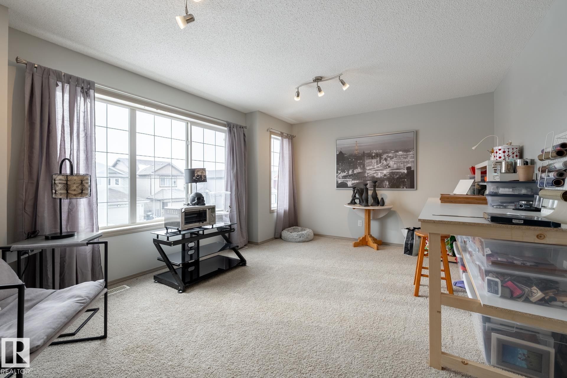 Sitting room with track lighting, light carpet, and a textured ceiling - 3312 17B Avenue, Edmonton, AB - Indoor