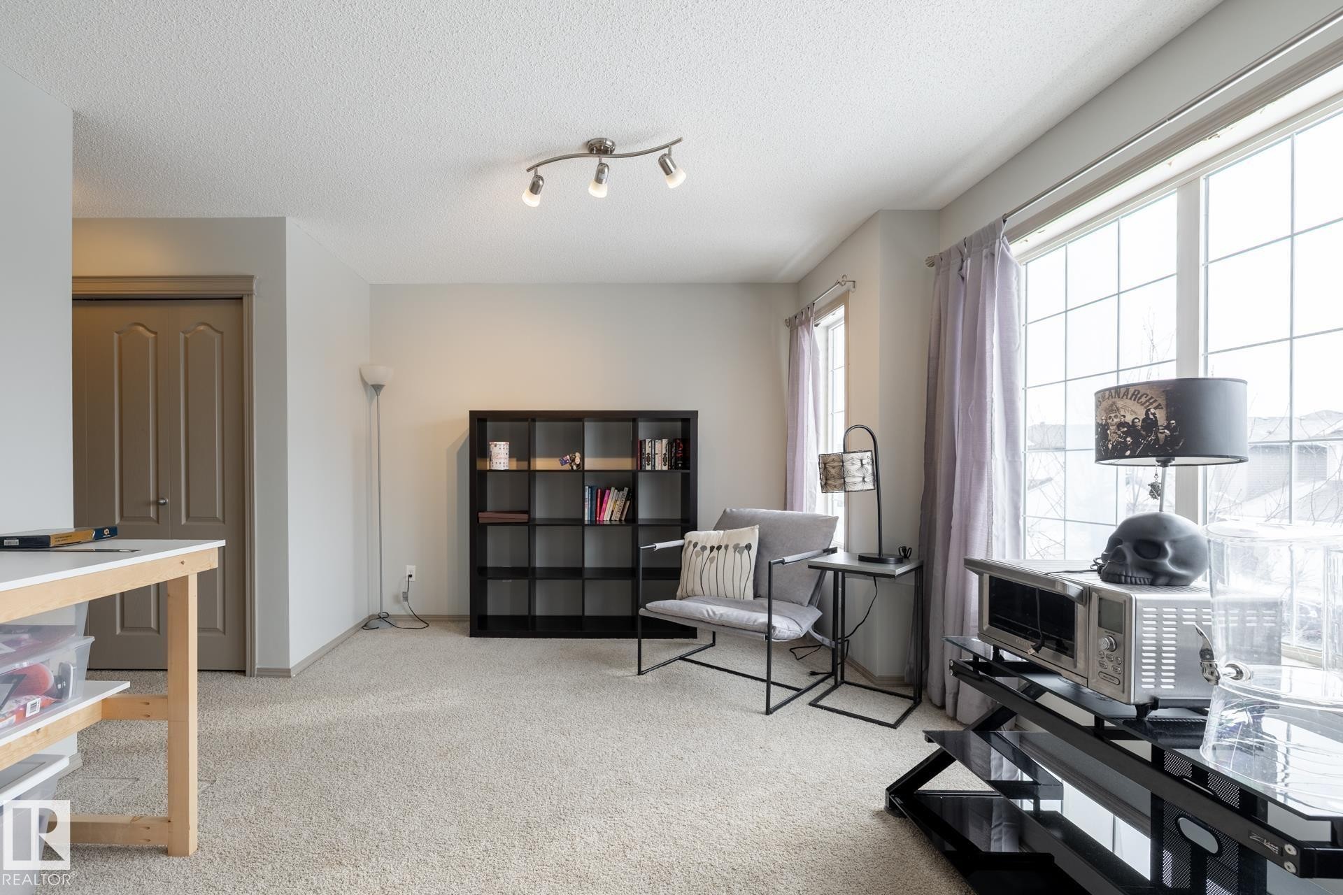 Living area featuring light colored carpet, a textured ceiling, and track lighting - 3312 17B Avenue, Edmonton, AB - Indoor