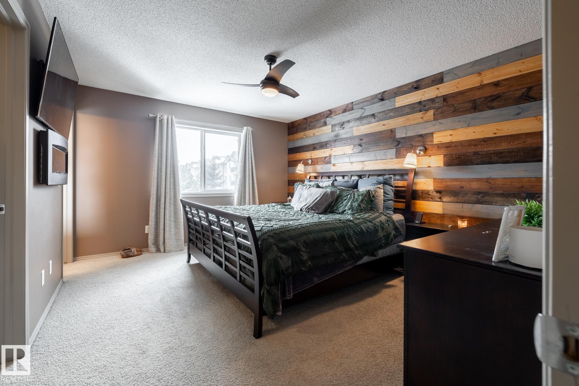 Carpeted bedroom with wood walls, a textured ceiling, and ceiling fan - 3312 17B Avenue, Edmonton, AB - Indoor Photo Showing Bedroom