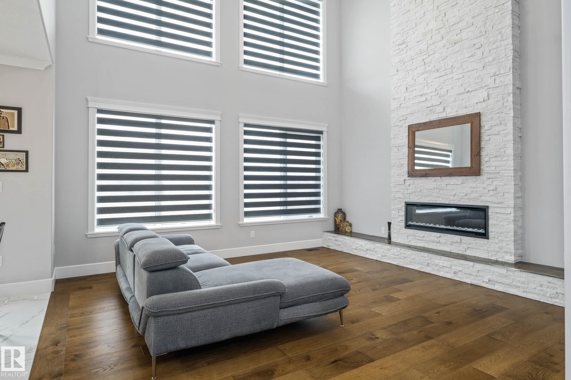 Living area featuring a high ceiling, dark wood-type flooring, and a fireplace - 4086 Whispering River Drive, Edmonton, AB - Indoor Photo Showing Living Room With Fireplace