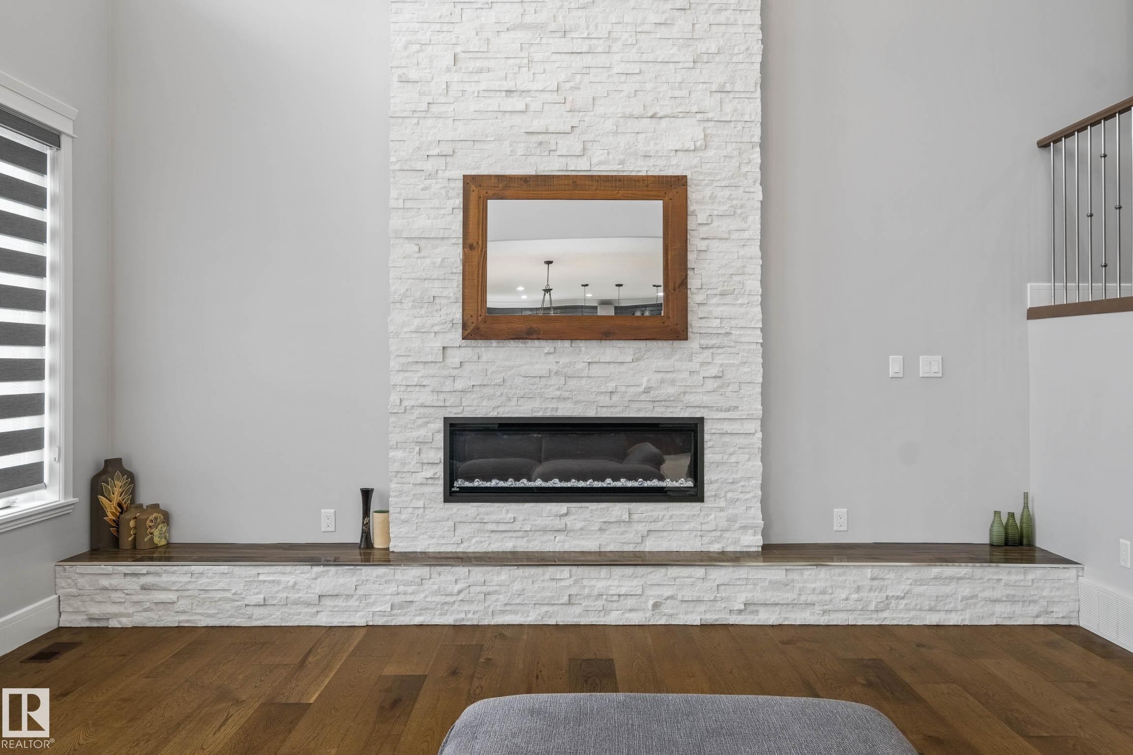 Living area featuring a stone fireplace and wood-type flooring - 4086 Whispering River Drive, Edmonton, AB - Indoor Photo Showing Living Room With Fireplace