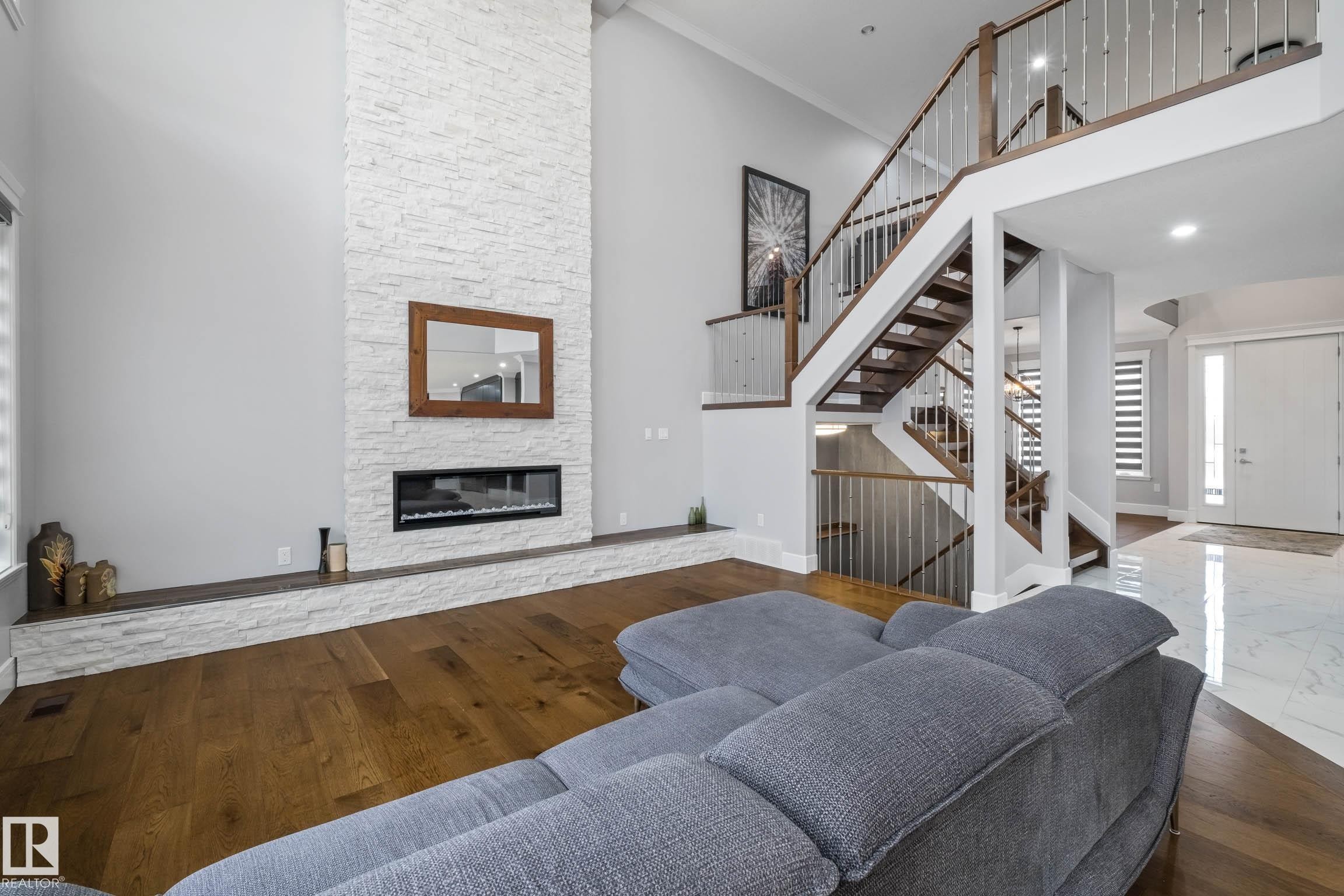 Living room with a high ceiling, a stone fireplace, and dark wood-type flooring - 4086 Whispering River Drive, Edmonton, AB - Indoor Photo Showing Living Room With Fireplace