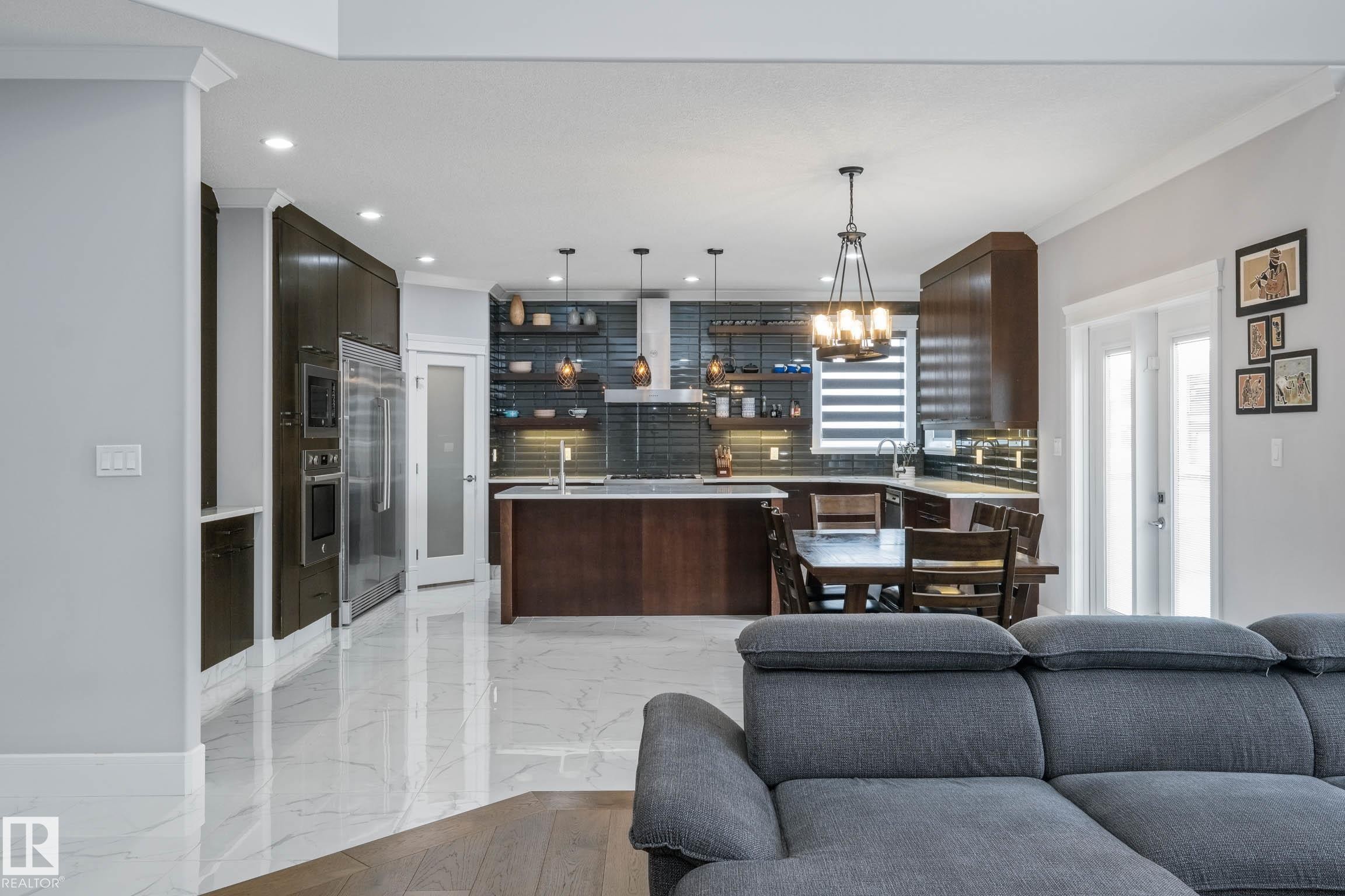 Kitchen with a kitchen island with sink, dark wood finish cabinetry, open shelves, open floor plan, and ornamental molding - 4086 Whispering River Drive, Edmonton, AB - Indoor Photo Showing Living Room