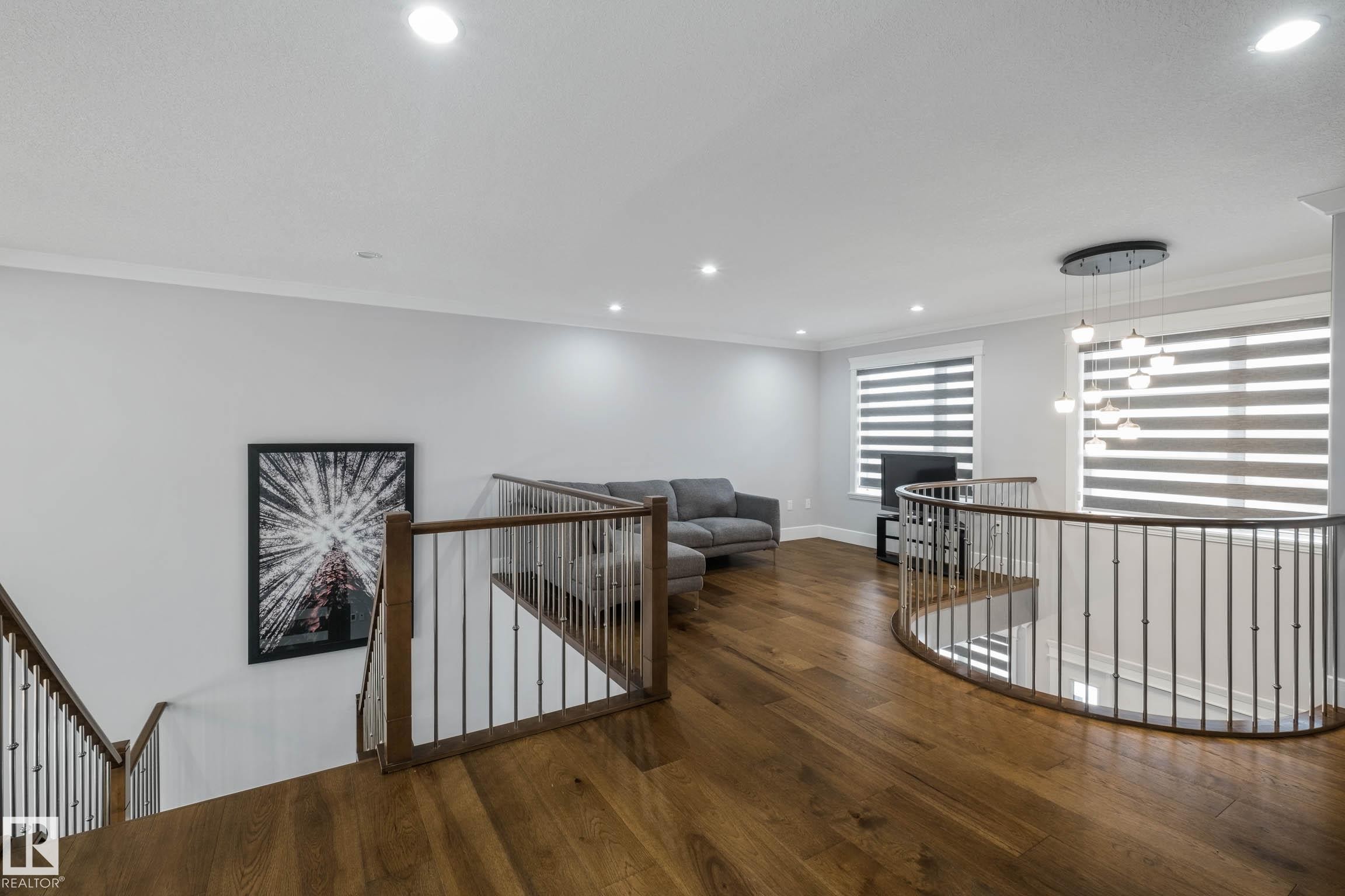 Hall featuring an upstairs landing, hardwood / wood-style floors, ornamental molding, and suspended lighting - 4086 Whispering River Drive, Edmonton, AB - Indoor Photo Showing Other Room