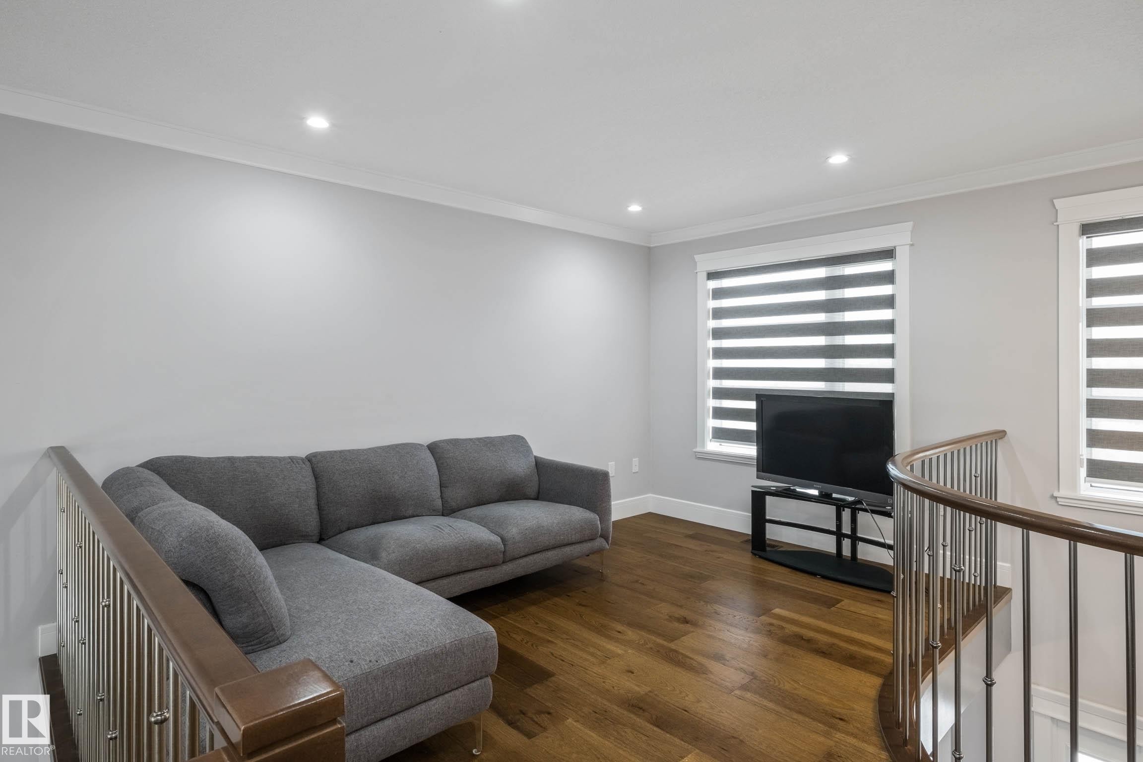 Living room with dark wood finished floors, crown molding, and recessed lighting - 4086 Whispering River Drive, Edmonton, AB - Indoor