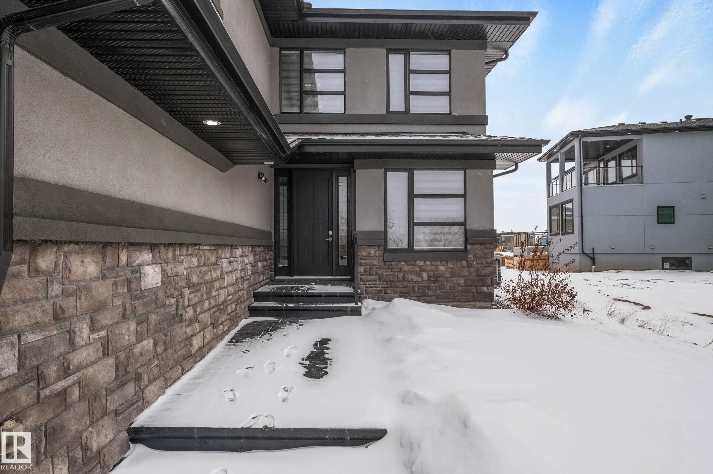 Snow covered property entrance featuring stone siding and stucco siding - 4086 Whispering River Drive, Edmonton, AB - Outdoor