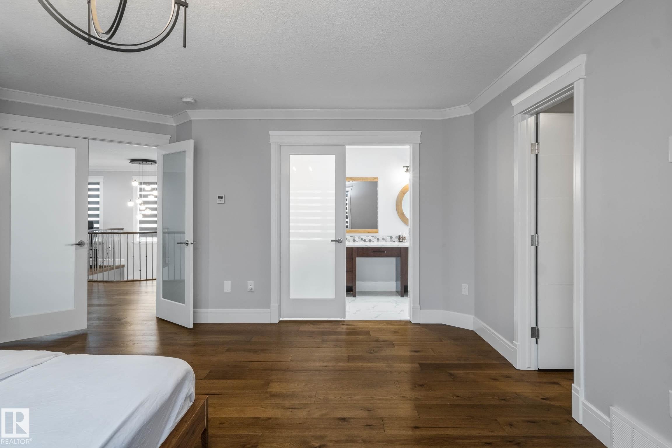 Bedroom with crown molding, dark wood-style floors, suspended lighting, french doors, and a textured ceiling - 4086 Whispering River Drive, Edmonton, AB - Indoor Photo Showing Other Room