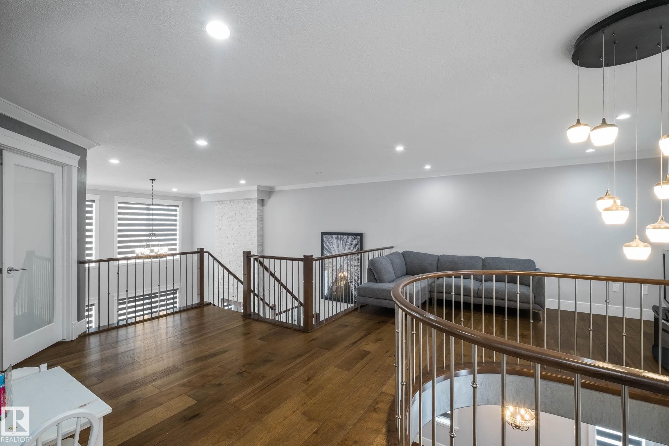 Hall featuring an upstairs landing, dark wood-type flooring, crown molding, and hanging lights - 4086 Whispering River Drive, Edmonton, AB - Indoor Photo Showing Other Room
