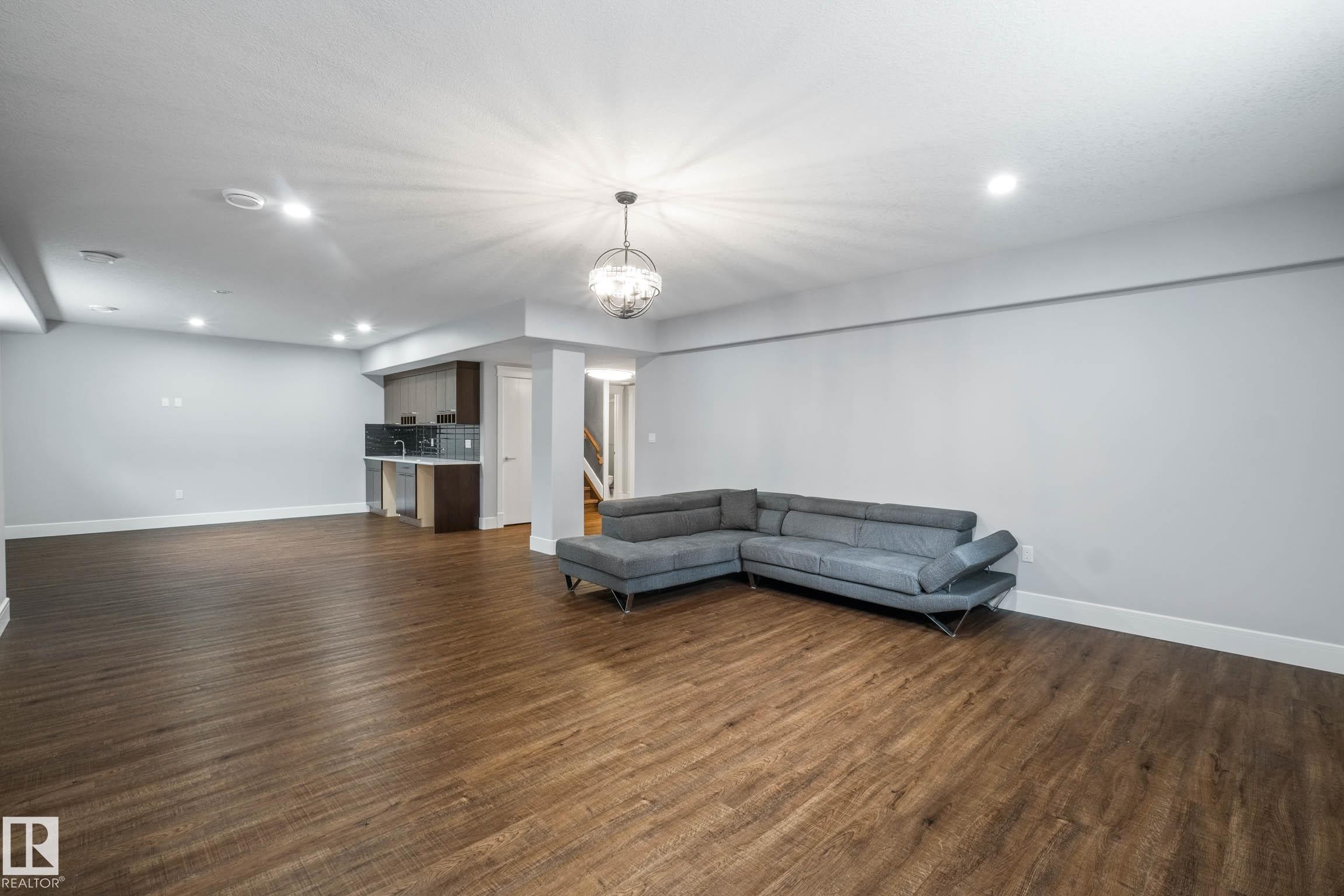 Unfurnished living room with dark wood finished floors and suspended lighting - 4086 Whispering River Drive, Edmonton, AB - Indoor