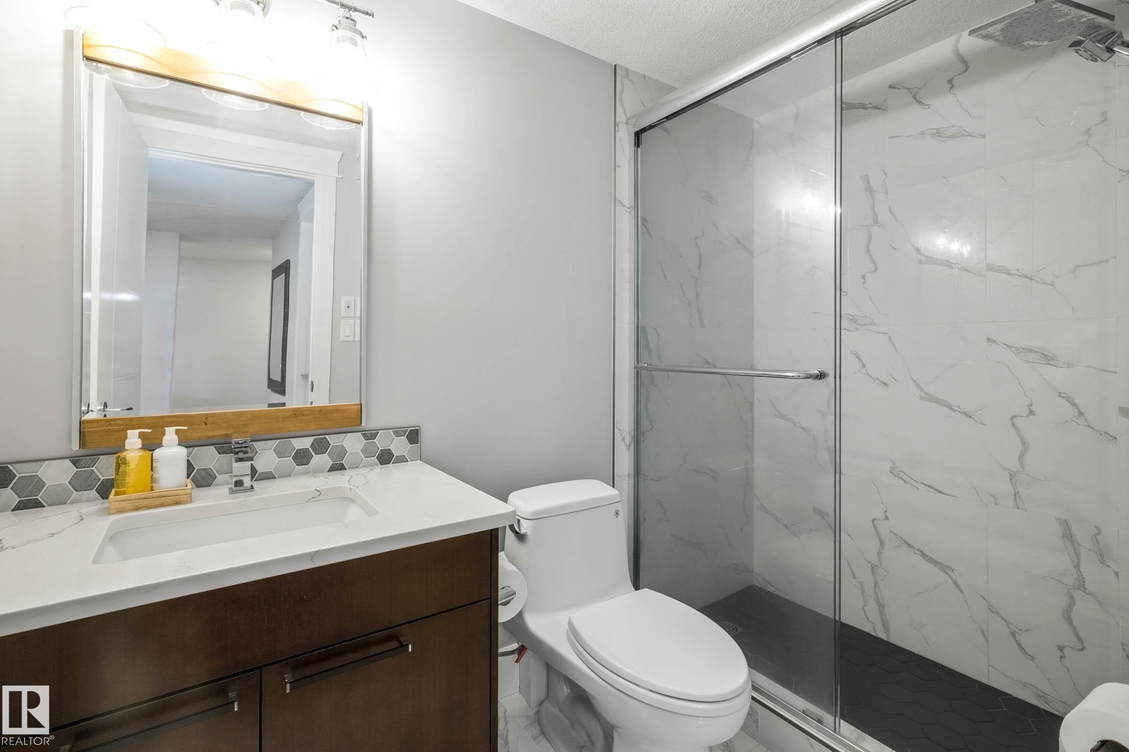 Bathroom featuring vanity, a marble finish shower, and decorative backsplash - 4086 Whispering River Drive, Edmonton, AB - Indoor Photo Showing Bathroom