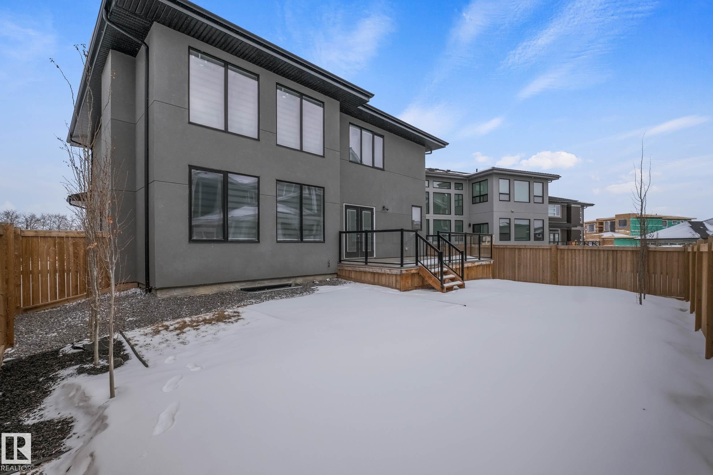 Snow covered property with a fenced backyard, stucco siding, and a deck - 4086 Whispering River Drive, Edmonton, AB - Outdoor With Exterior