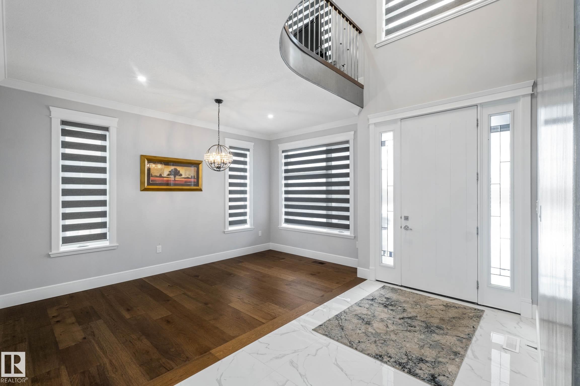 Foyer entrance featuring dark marble finish flooring, healthy amount of natural light, hanging lights, and crown molding - 4086 Whispering River Drive, Edmonton, AB - Indoor Photo Showing Other Room