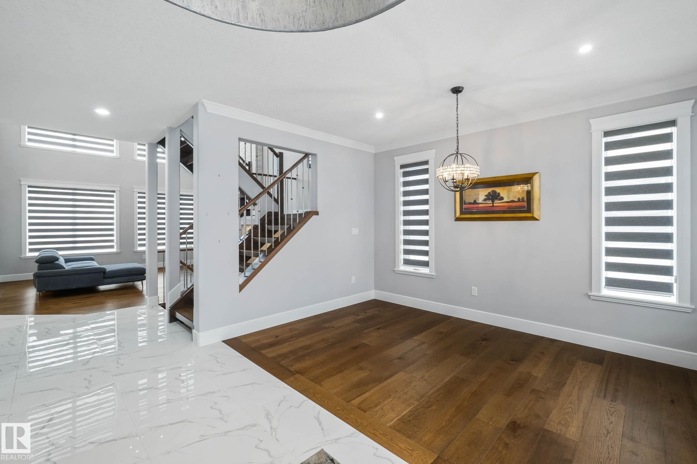 Unfurnished dining area with dark wood-style floors, crown molding, and suspended lighting - 4086 Whispering River Drive, Edmonton, AB - Indoor Photo Showing Other Room